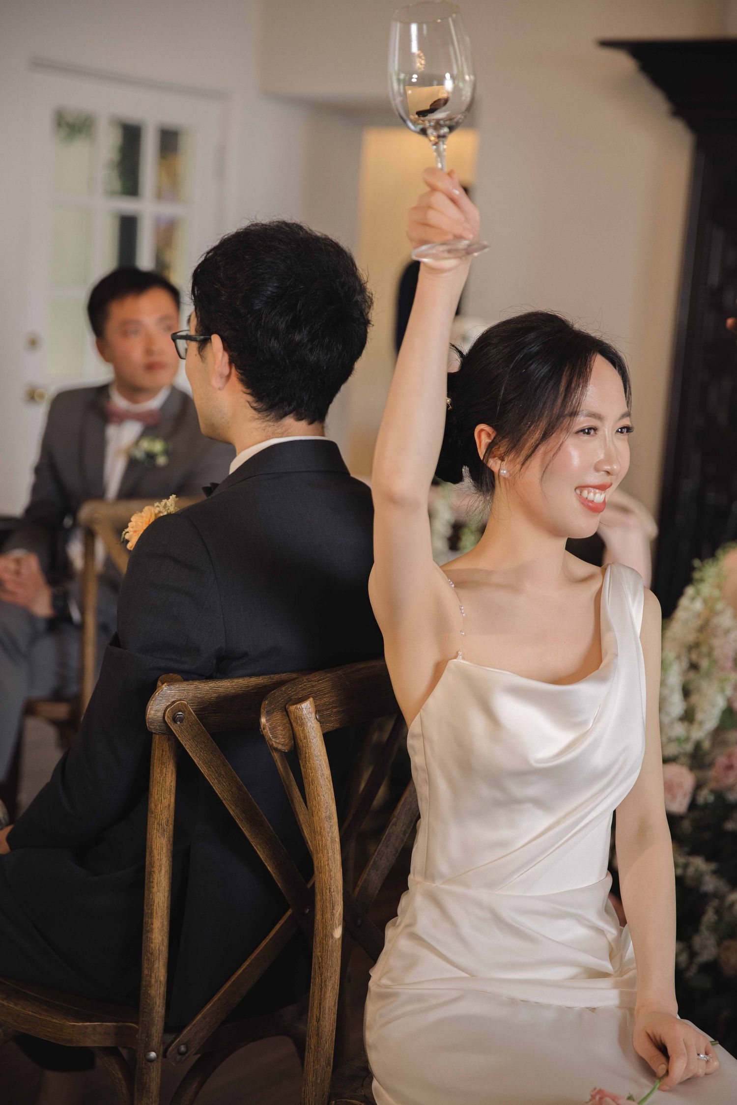 A person in a white dress raises their glass during a wedding celebration.