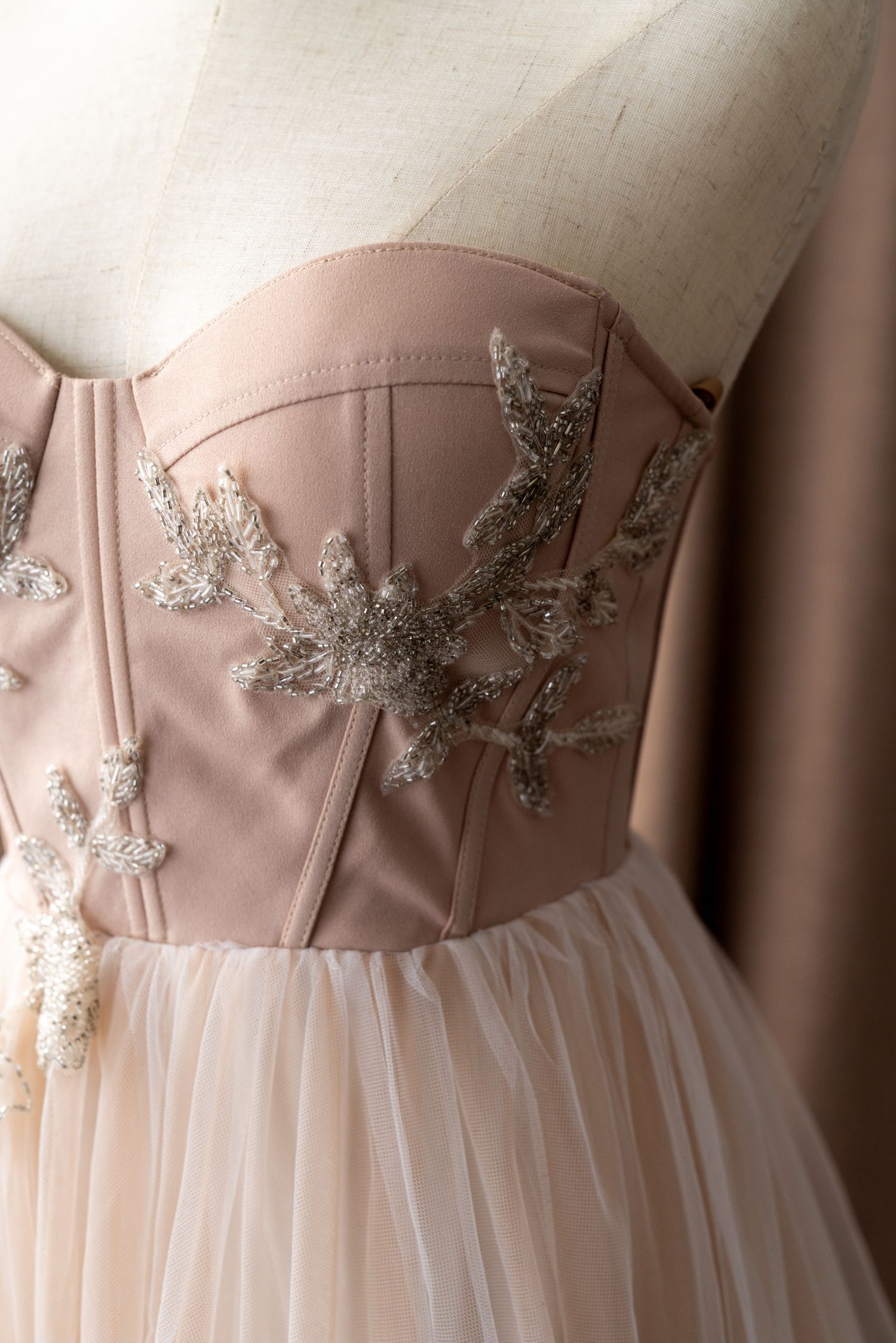 Blush pink bodice with silver embroidered appliques on a formal dress.