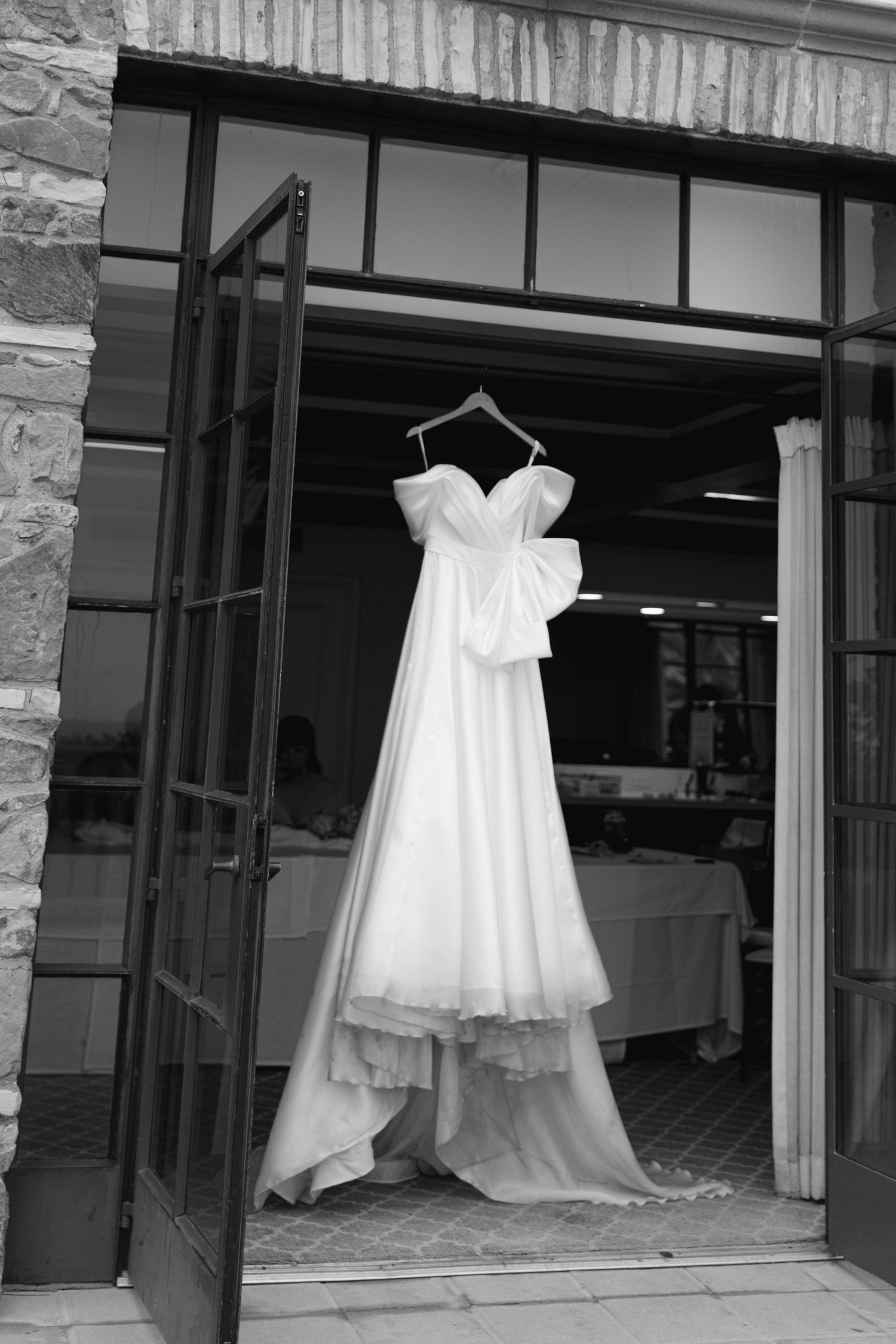 White wedding dresses hanging on display in a storefront window.