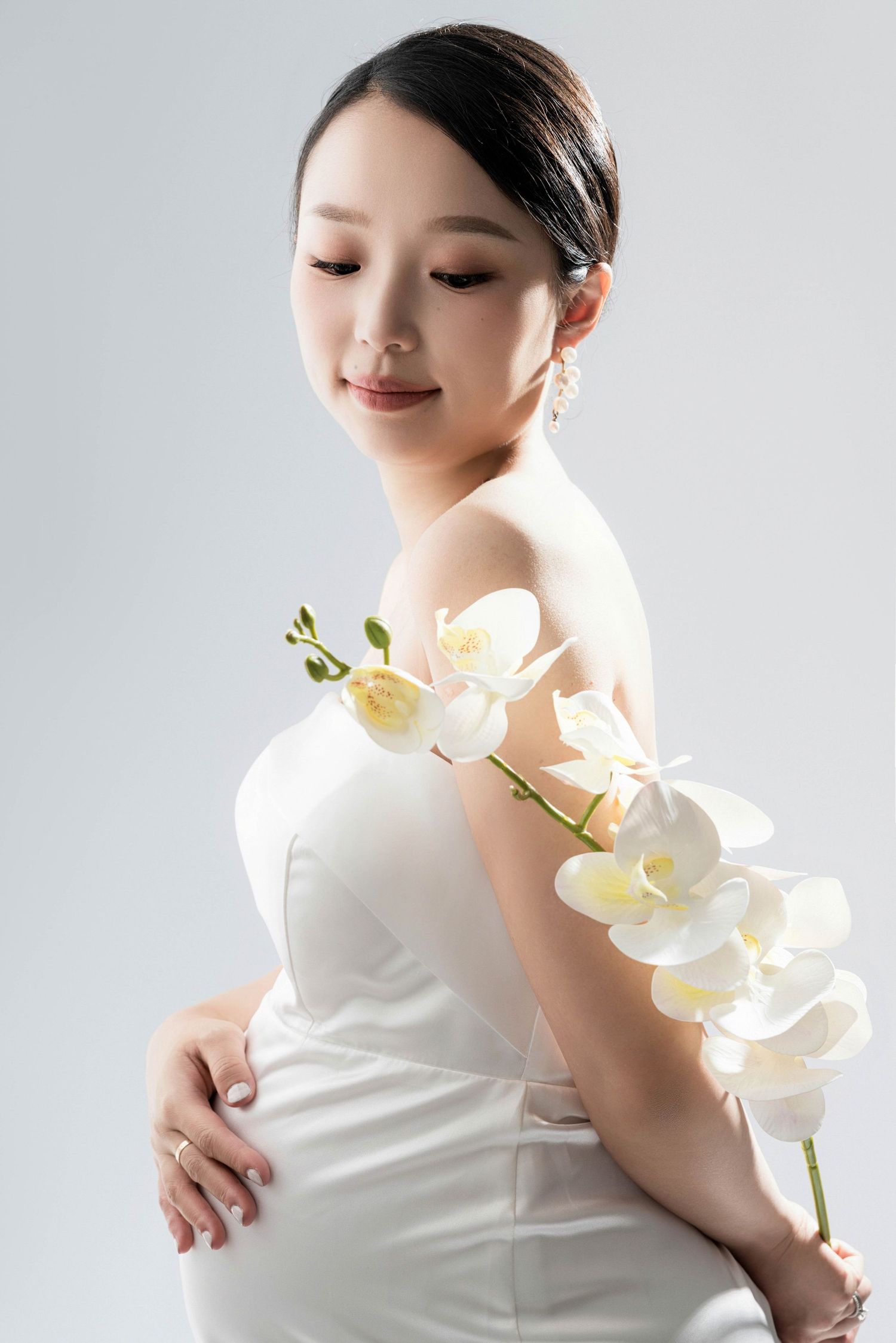Ethereal maternity photos with white orchids and flowing fabric.