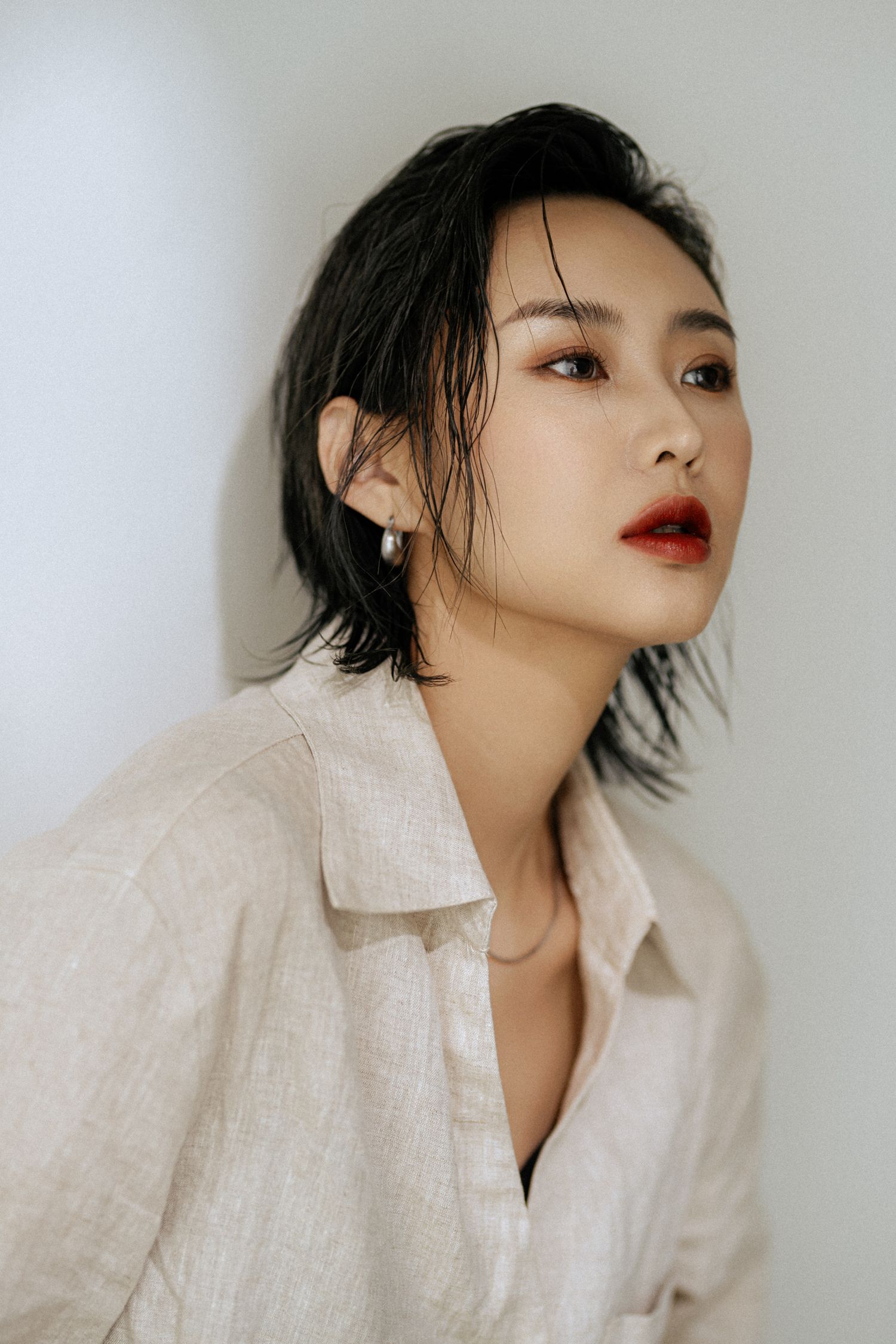 Close-up beauty shot featuring bold red lipstick and white linen collar.