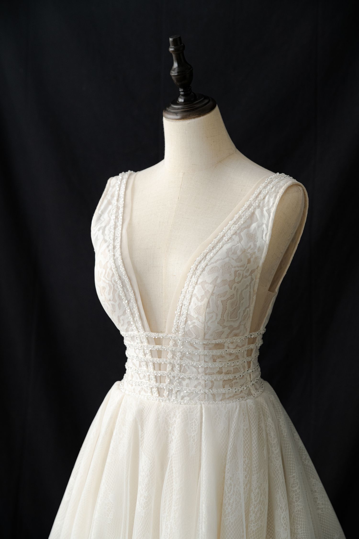 Detailed shot of wedding dress bodice featuring deep V-neckline and lace appliques.