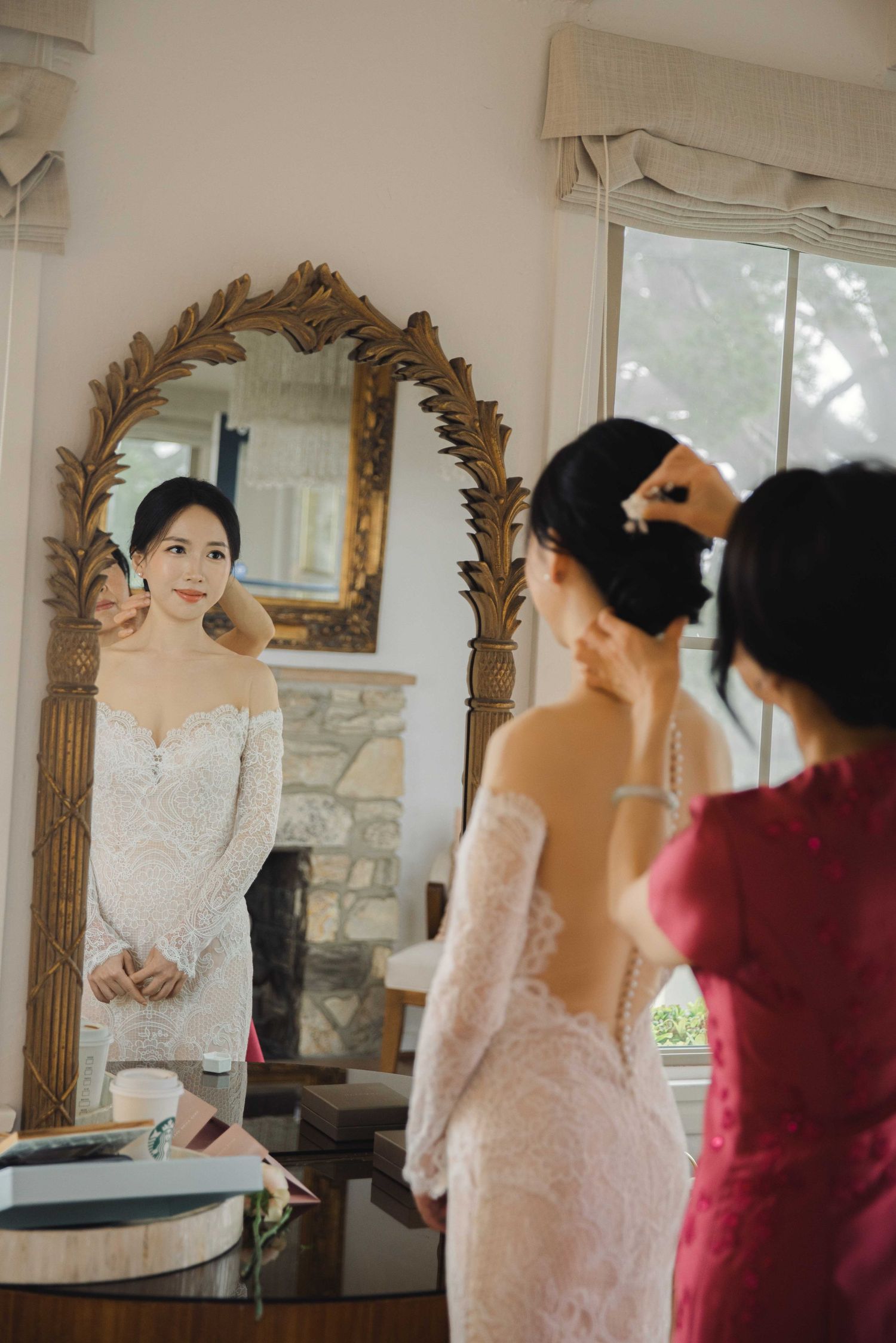 Wedding dress fitting session in elegant room with ornate gold mirror.