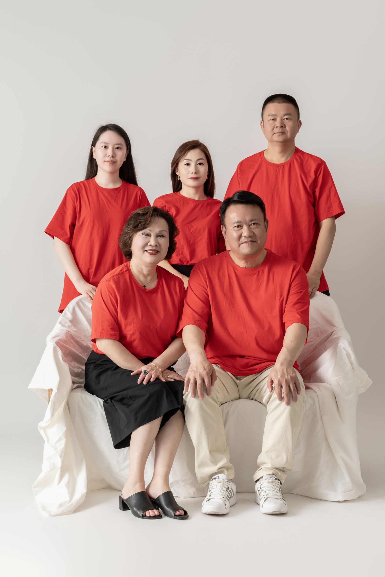 Family group portrait with members wearing matching red shirts and light colored pants.