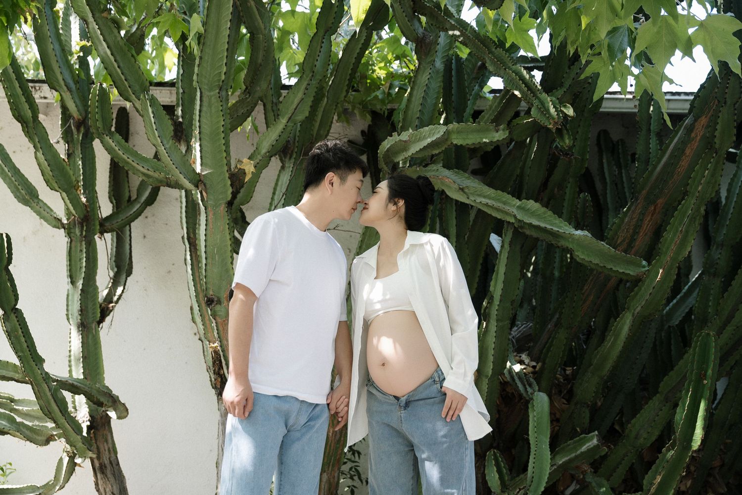 Casual outdoor maternity photos under green leafy trees.