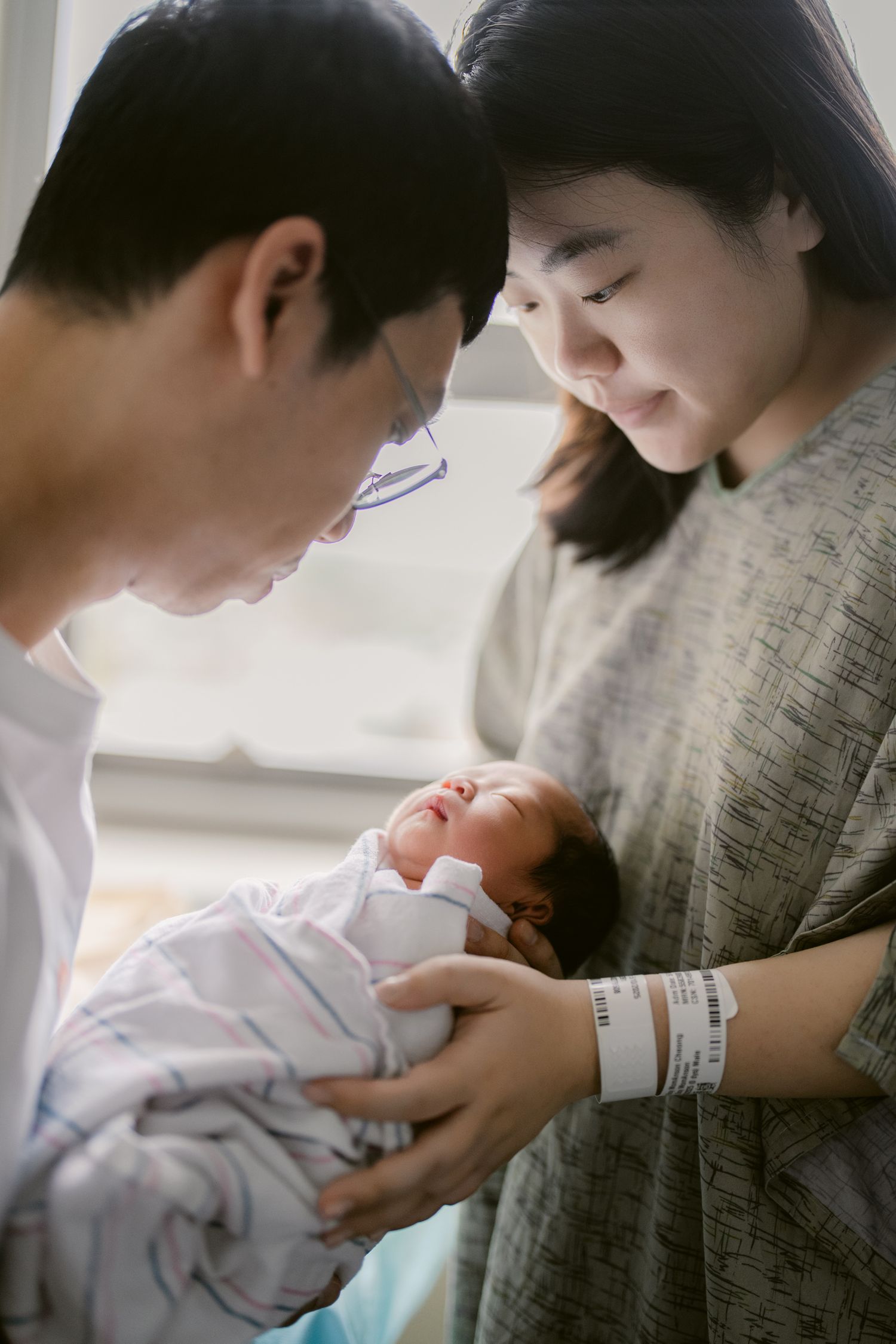 Parents gazing lovingly at their newborn baby in a series of intimate photographs.