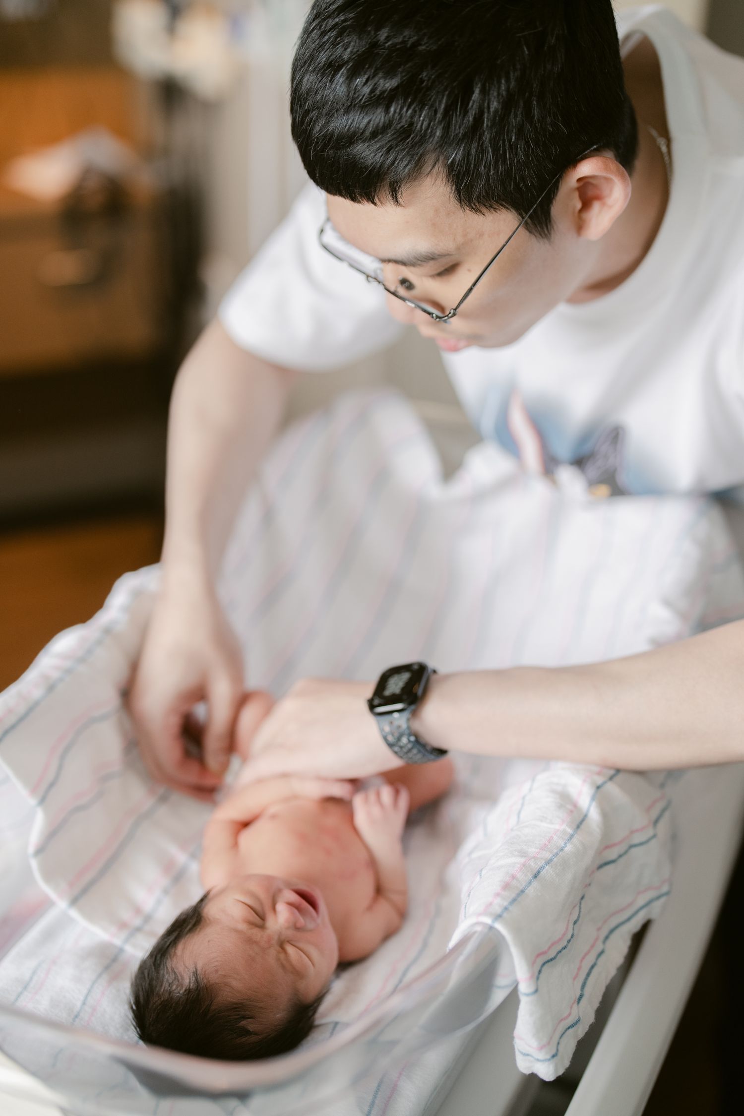 Healthcare worker provides care to a newborn in a hospital bassinet.