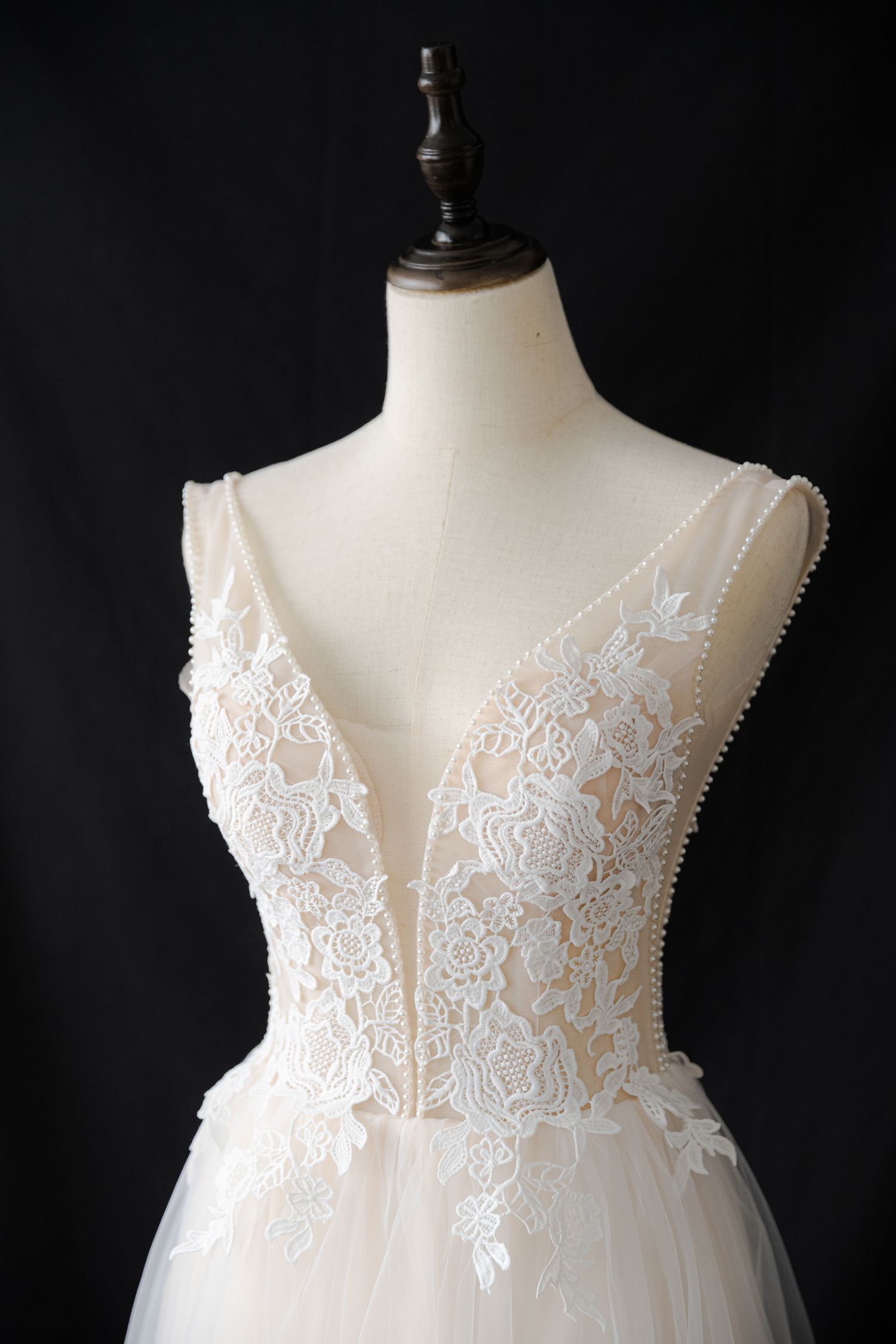 Close-up of intricate floral lace bodice detail on white tulle dress.