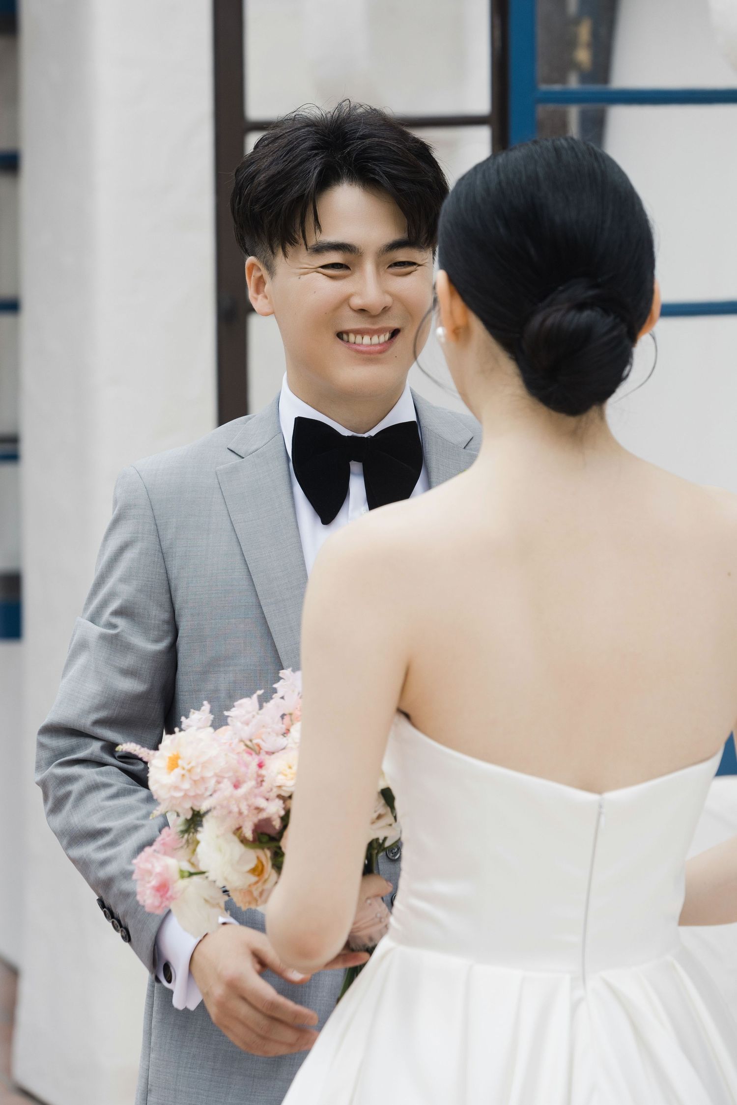 Romantic wedding moment captured between couple with bride in white dress and groom in grey suit.