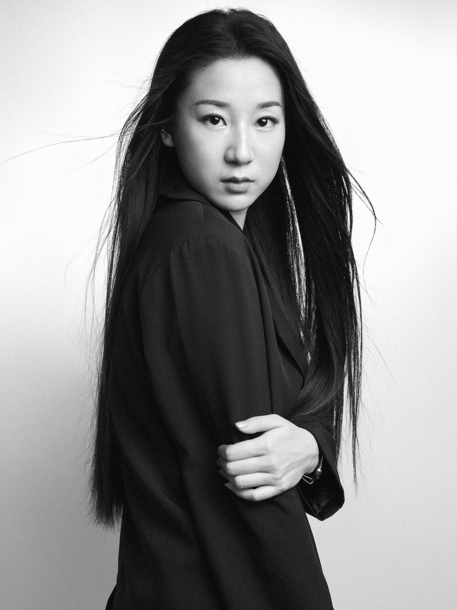 Artistic black and white portraits of woman in dark clothing with flowing hair.