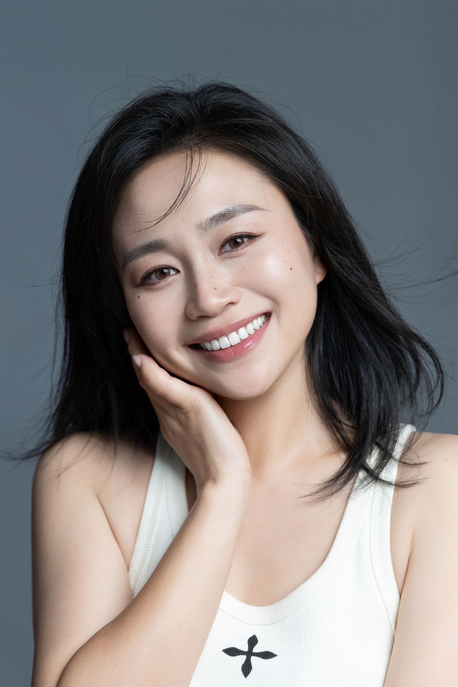 Expressive portrait with natural makeup and flowing dark hair.