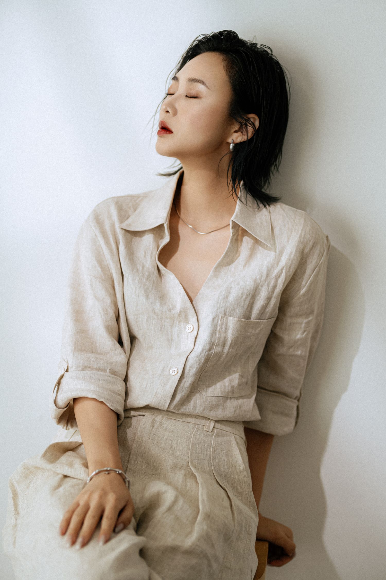 Dramatic fashion poses in cream linen outfit against white background.