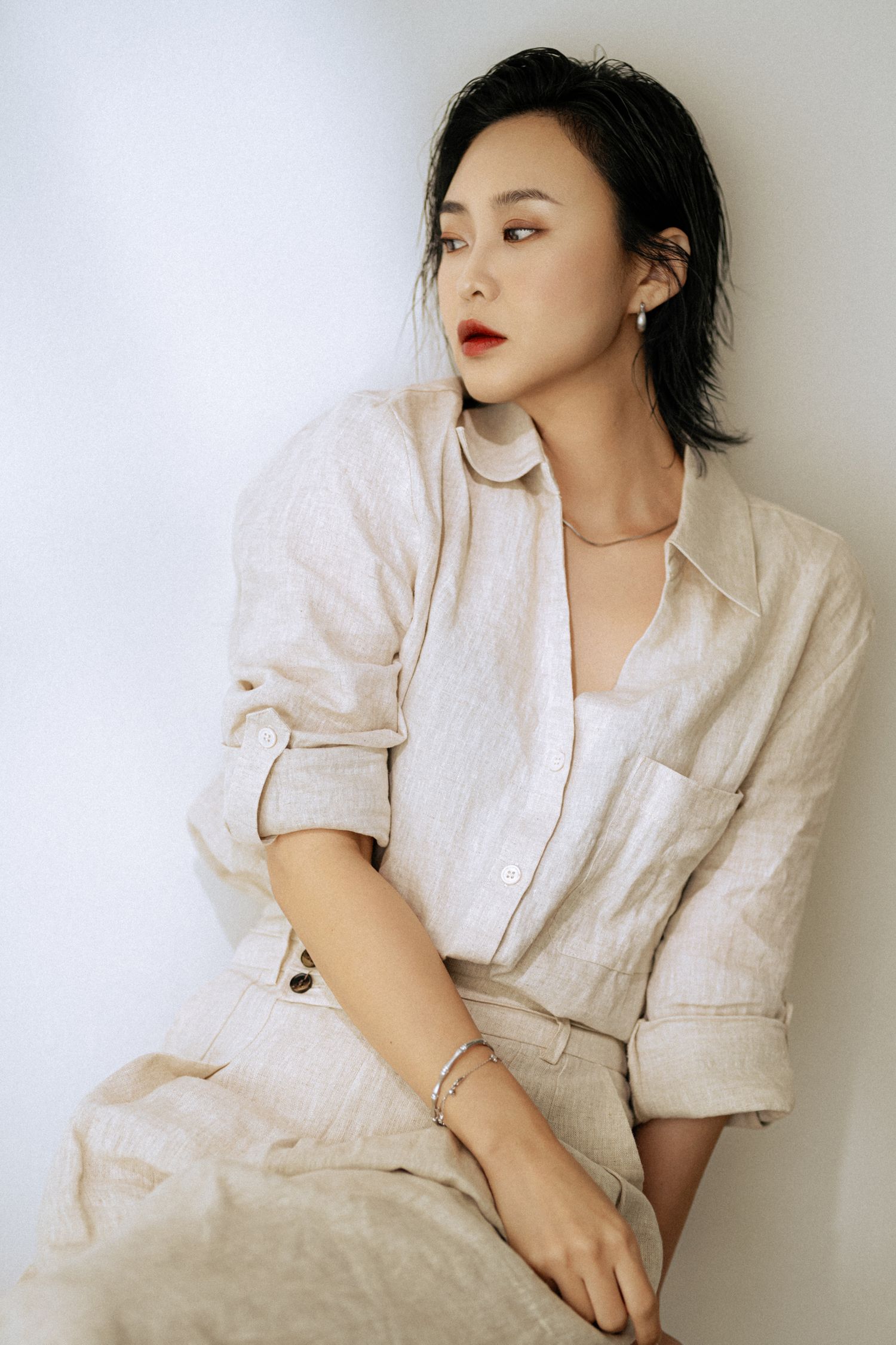 Minimalist fashion portrait in beige linen outfit with subtle jewelry accents.