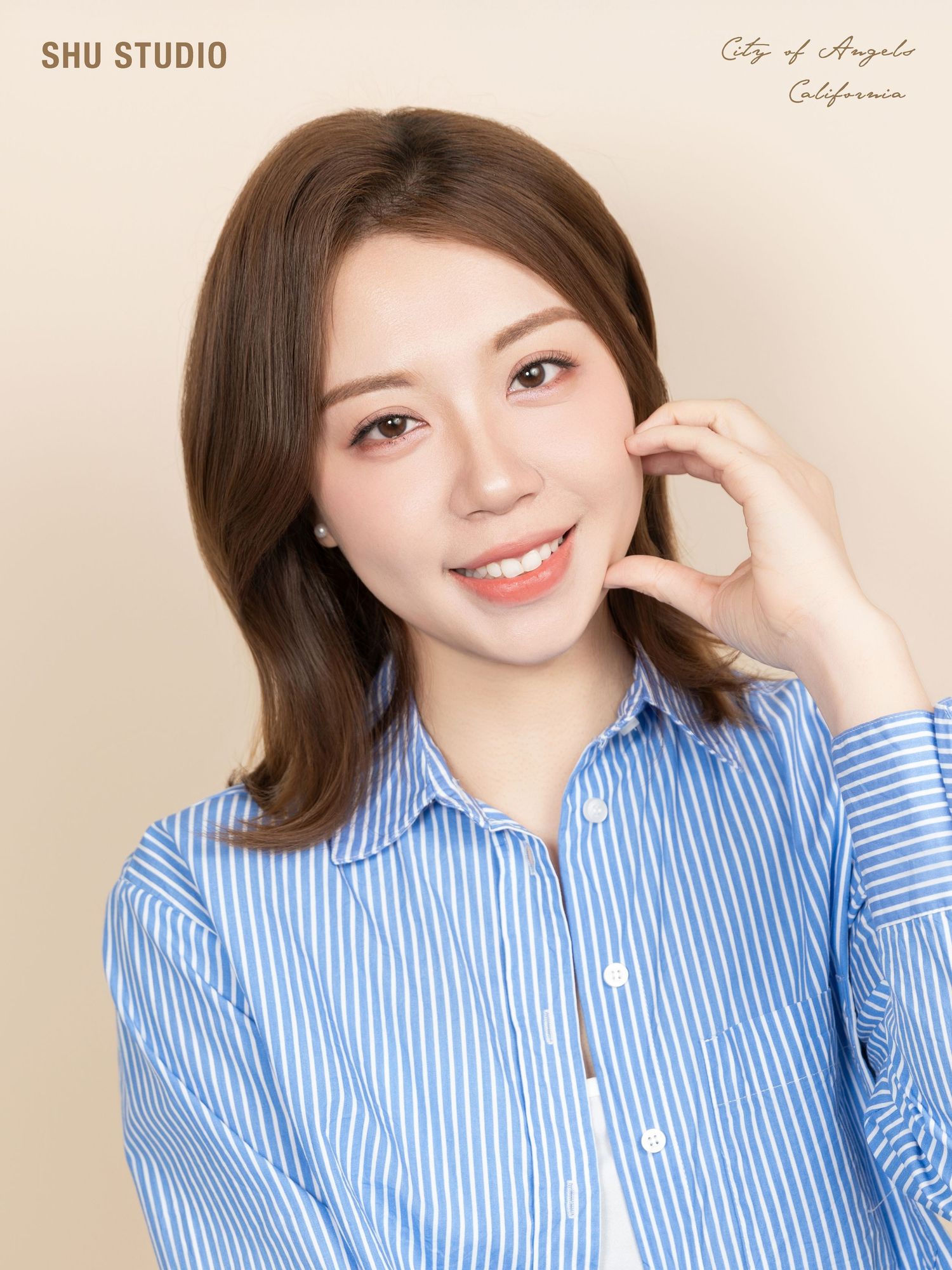 Professional portrait in blue and white striped button-down shirt against beige background.