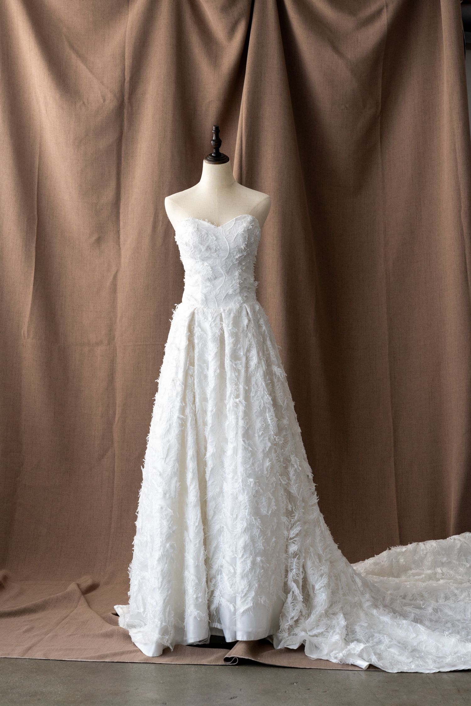 Strapless white lace wedding gown with sweetheart neckline and flowing train on display.