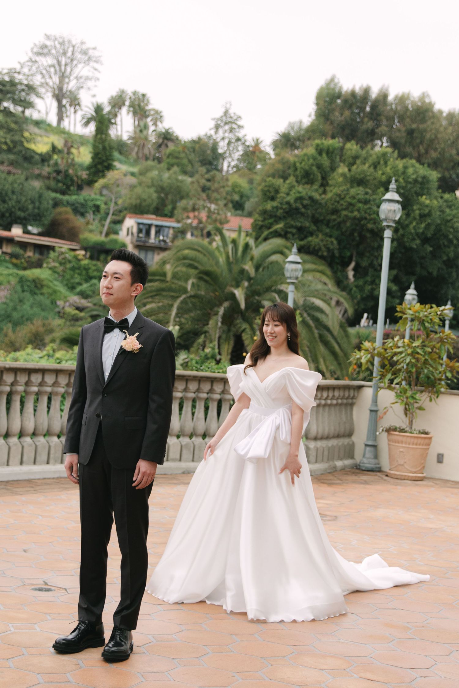 Romantic wedding portraits on a tiled terrace with tropical landscaping and stone railings.