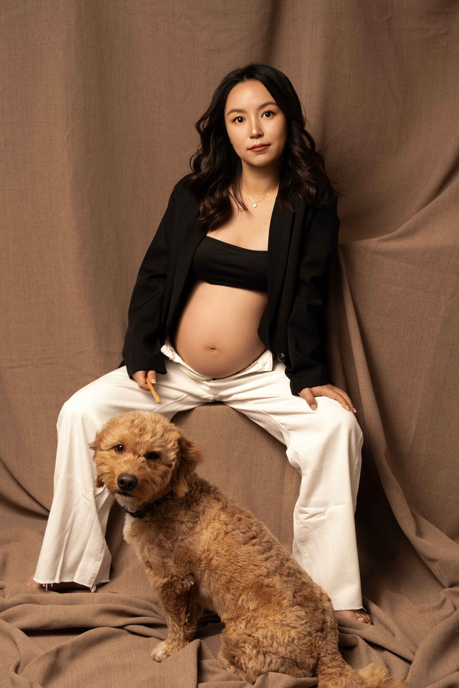 Maternity photoshoot featuring a brown fluffy dog and someone in black and white attire.