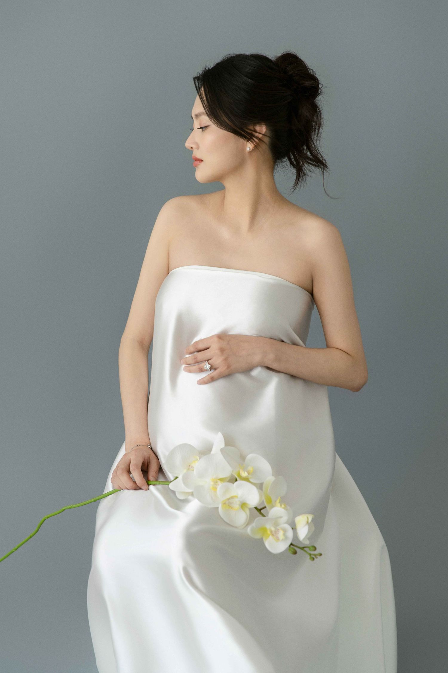 Elegant studio portrait with white orchid and minimalist fabric draping.