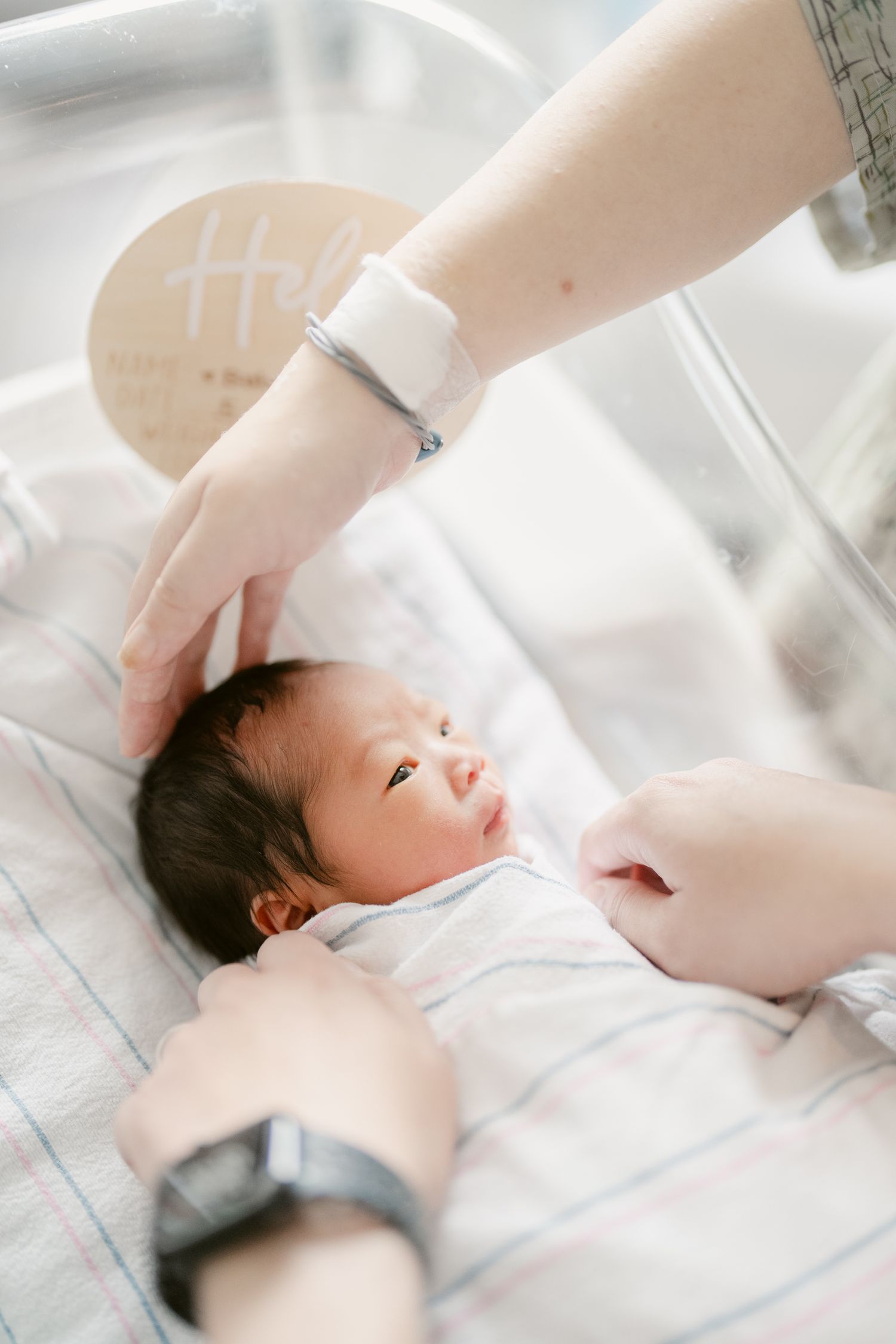 Healthcare provider checking vital signs of a newborn in hospital bassinet.