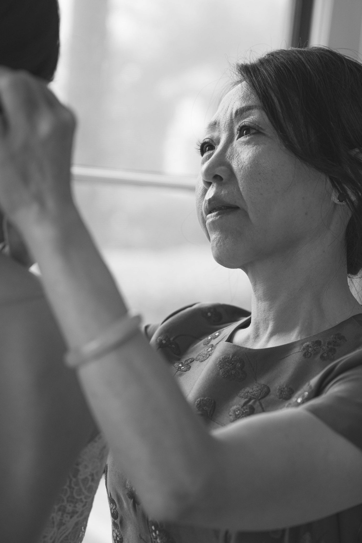 Black and white profile shot of someone dancing with raised arms at a celebration.
