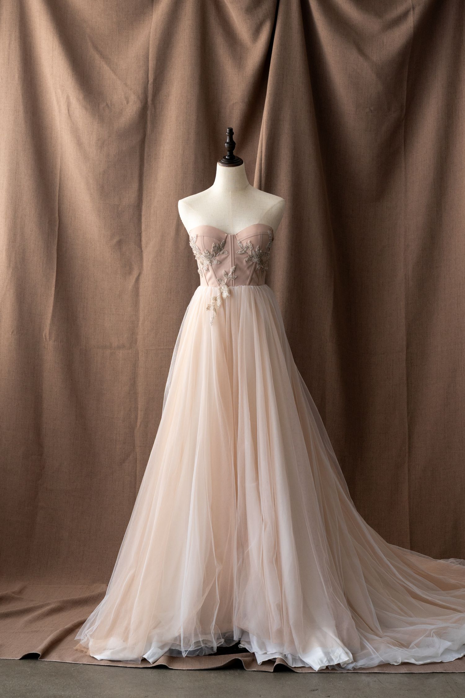 Ethereal blush wedding dress with flowing tulle skirt displayed on mannequin.
