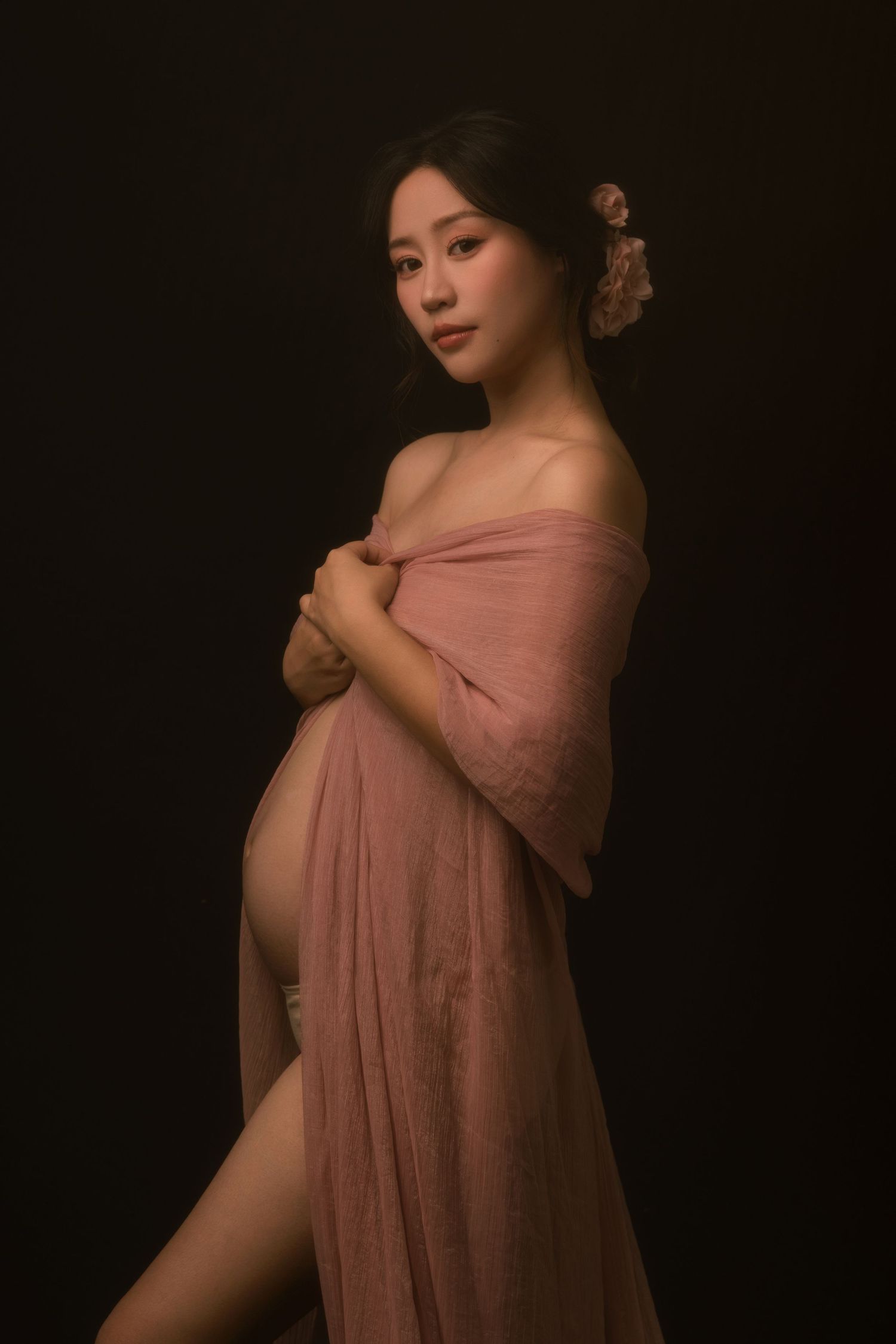 Artistic portrait in dusty pink fabric against dark background.