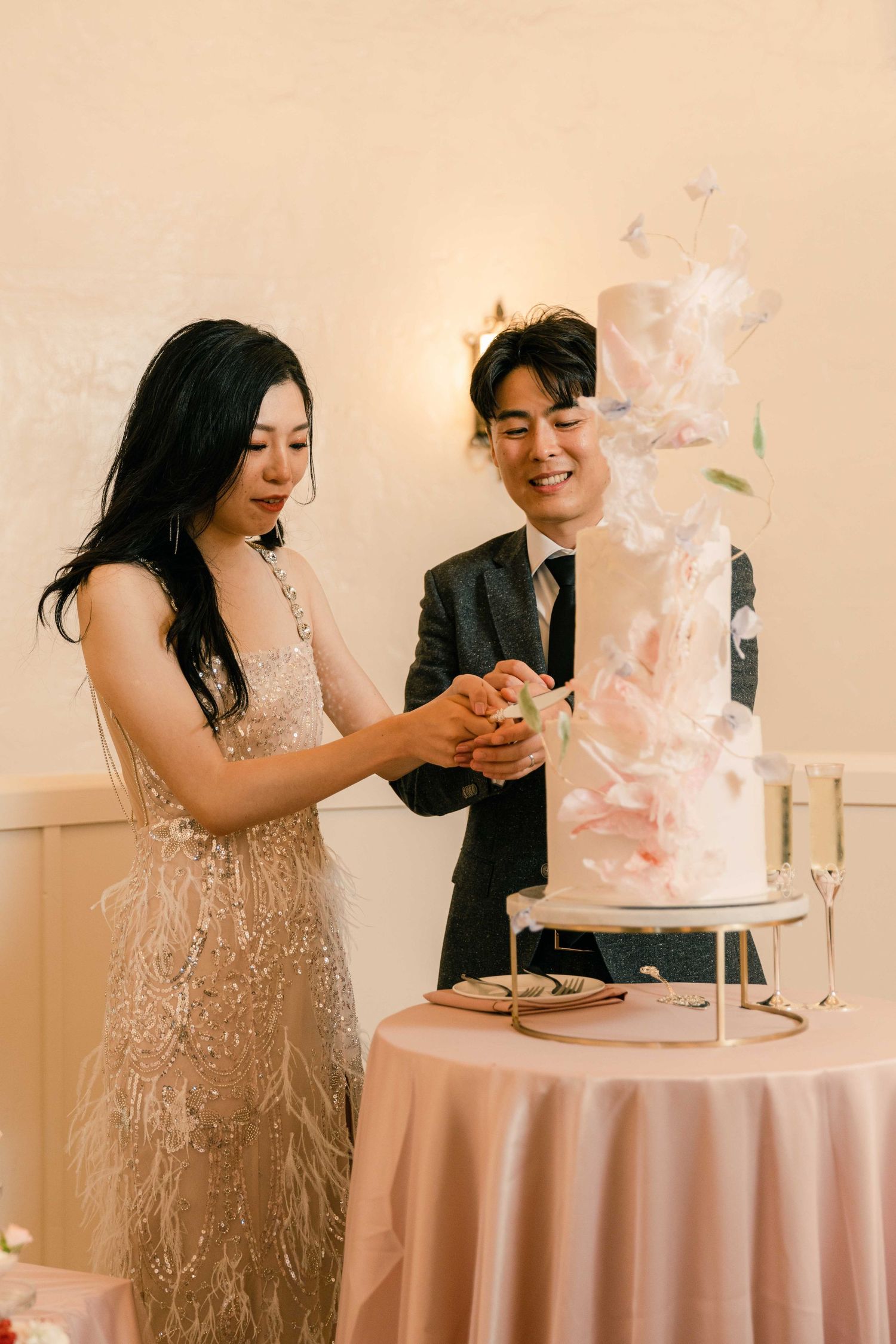 Wedding cake cutting moment with a delicate white and pink tiered cake.