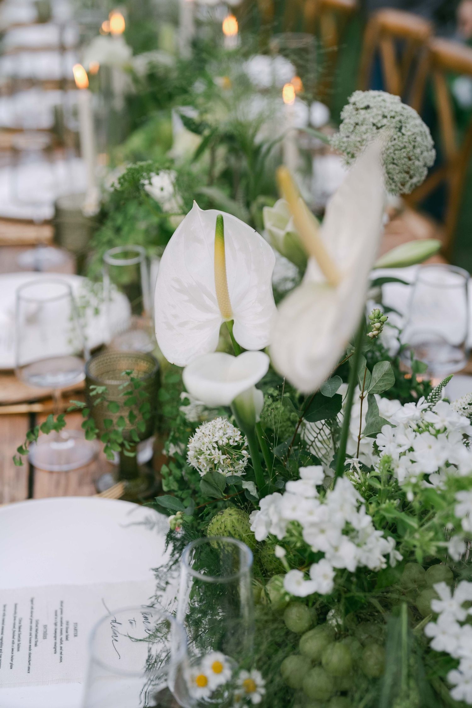 White floral centerpieces with tulips and mixed greenery on elegant table settings.