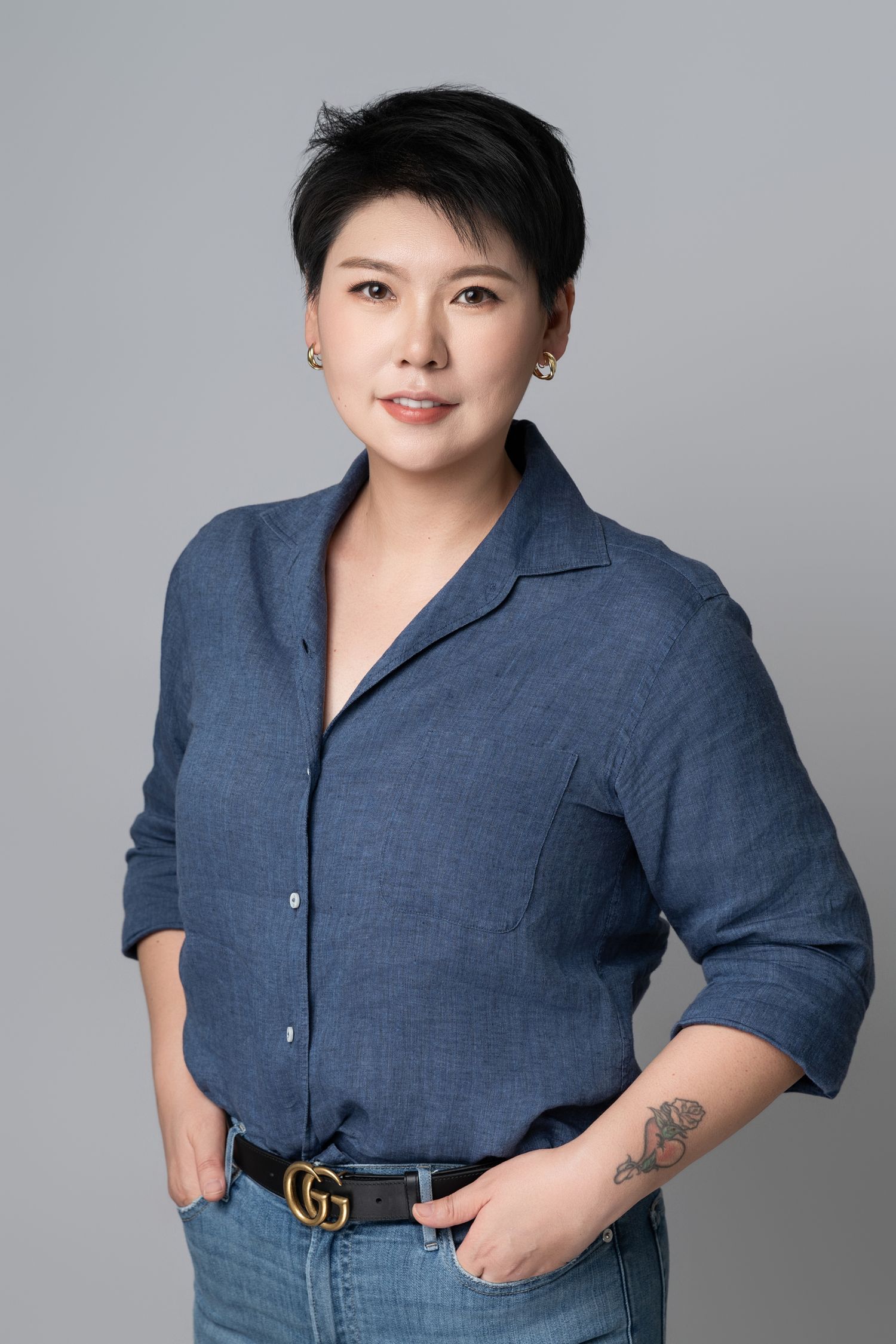 Casual business portrait of person in blue button-down shirt with Gucci belt.