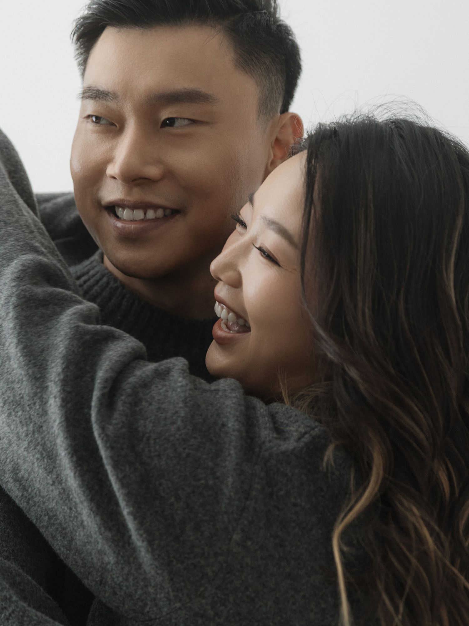 Sweet candid moments of a couple laughing and embracing in casual gray attire.