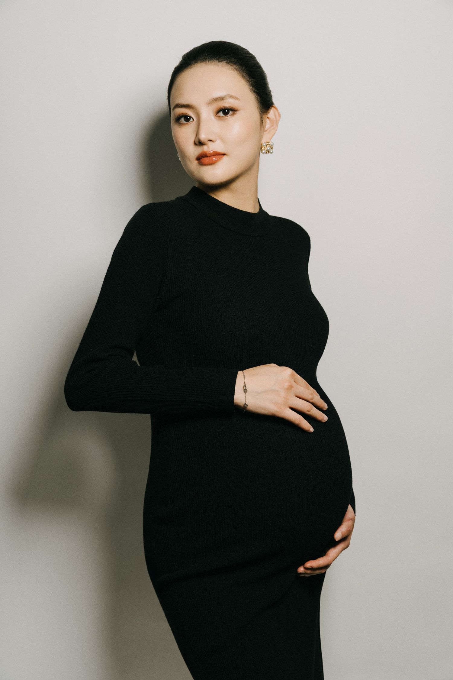 Minimalist maternity photos in black outfit against white background showing different poses.