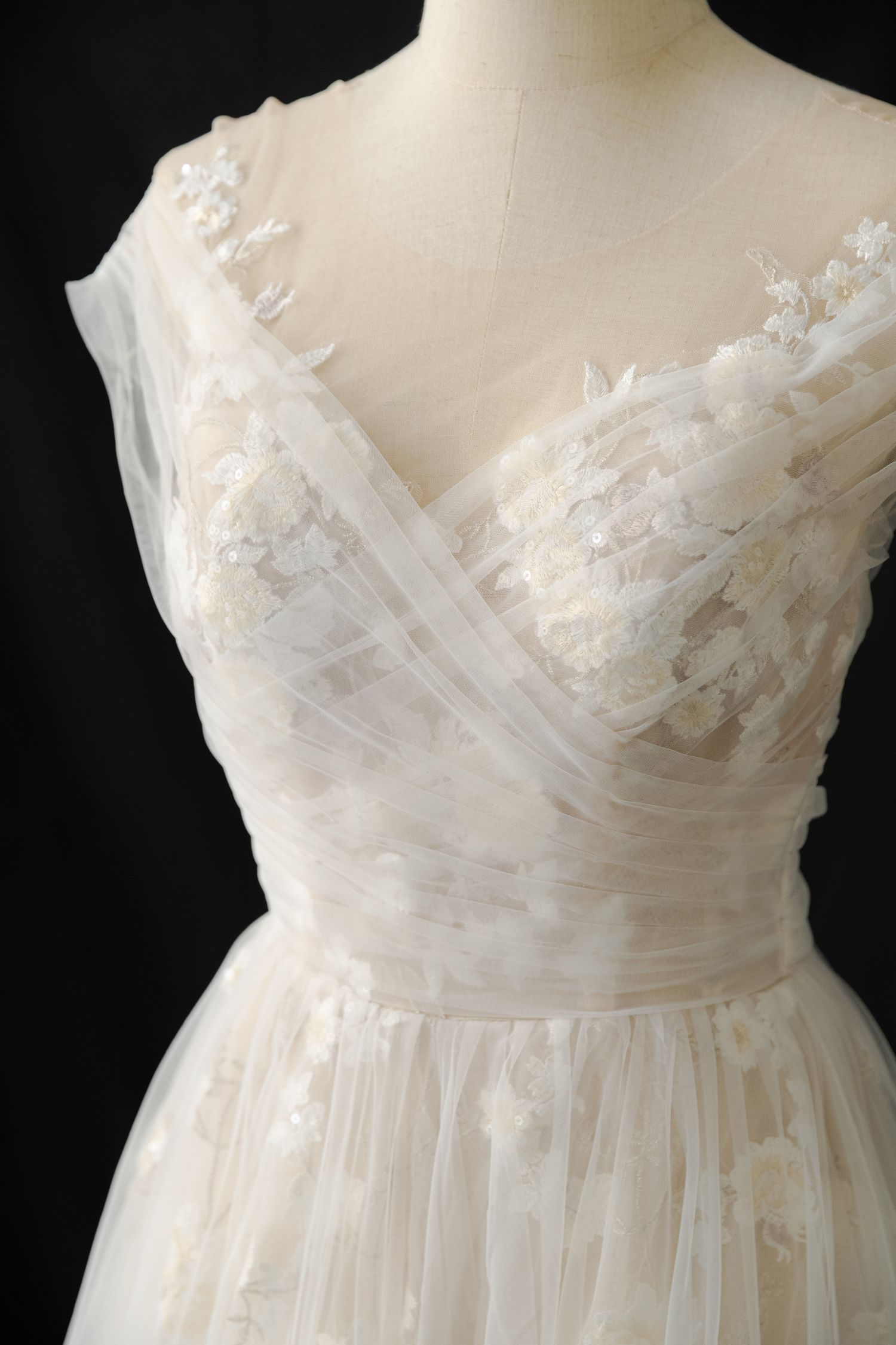 Delicate white wedding dress bodice with sweetheart neckline and floral lace appliques shown in detail.