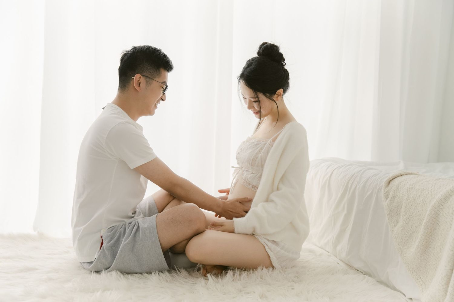 Intimate maternity session with couple in white and grey casual wear.
