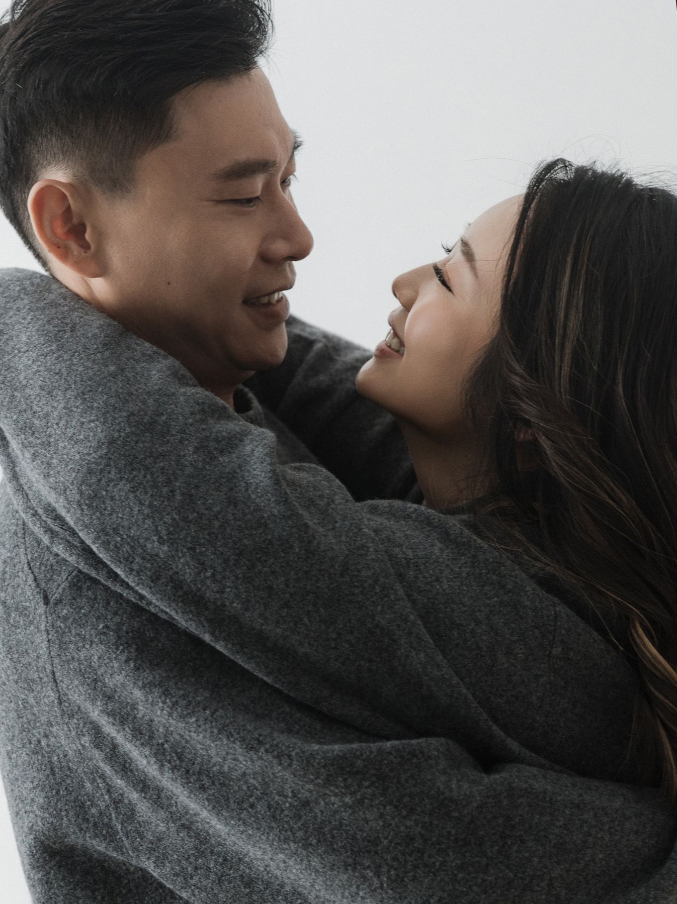 Couple embracing tenderly while wearing matching gray sweaters.