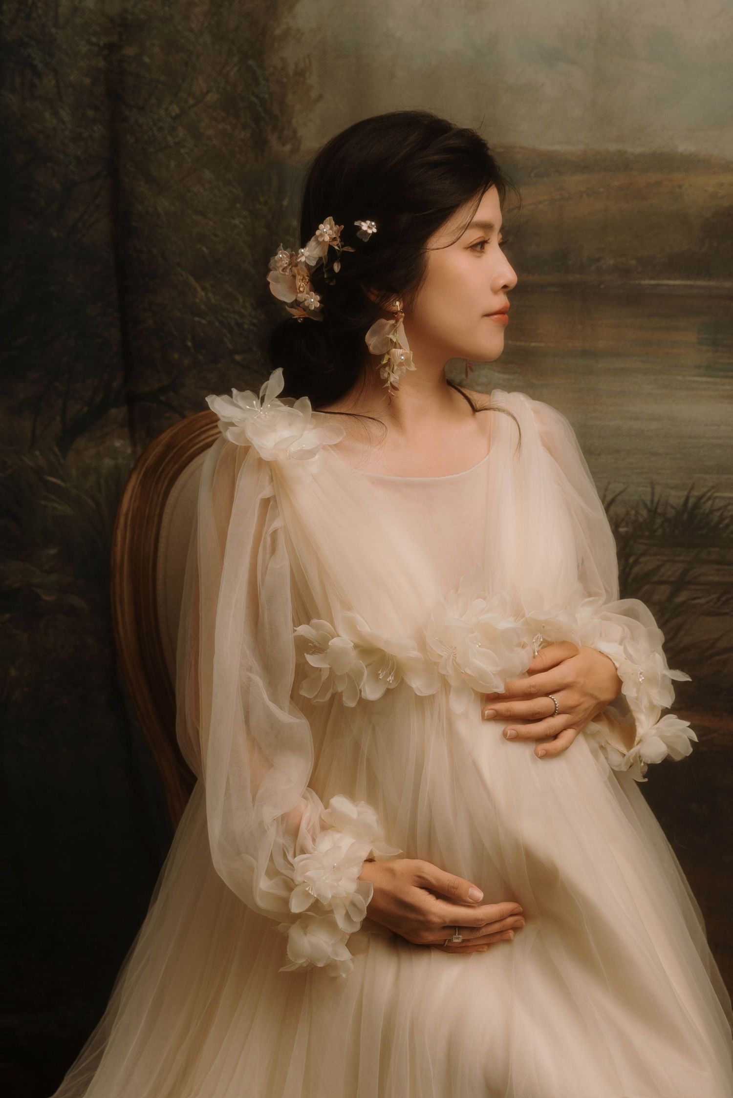 Vintage-inspired maternity portrait with ruffled cream dress and floral details.