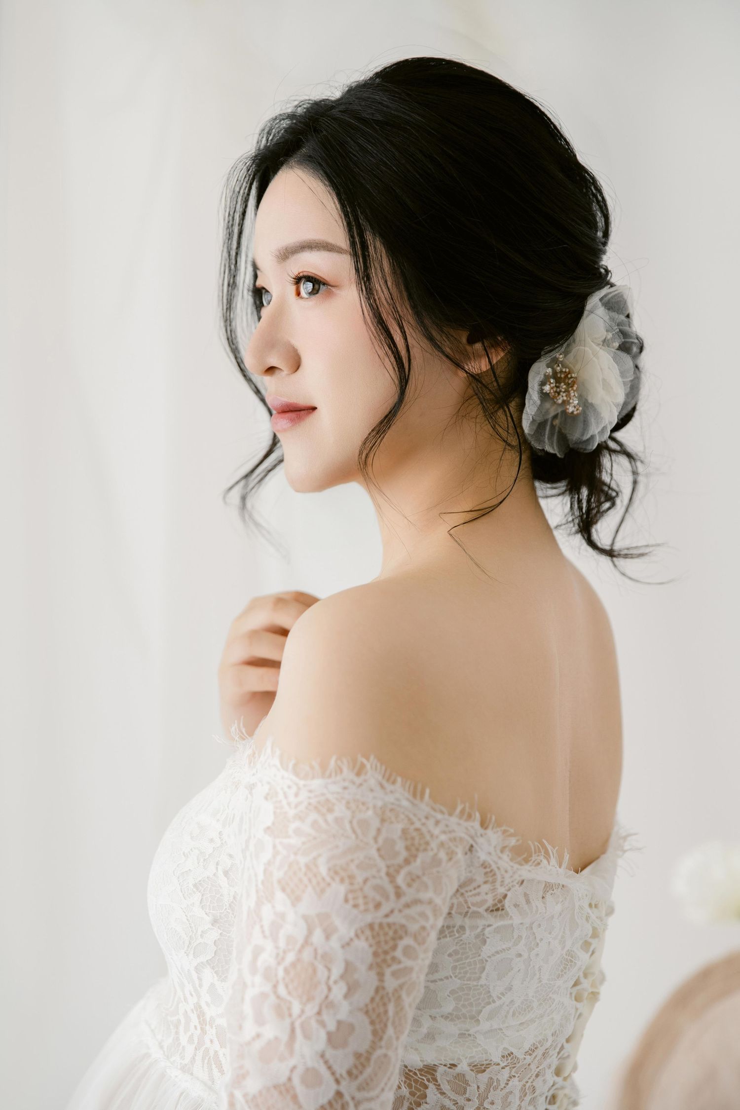 Romantic bridal portrait featuring off-shoulder lace gown and soft updo hairstyle.