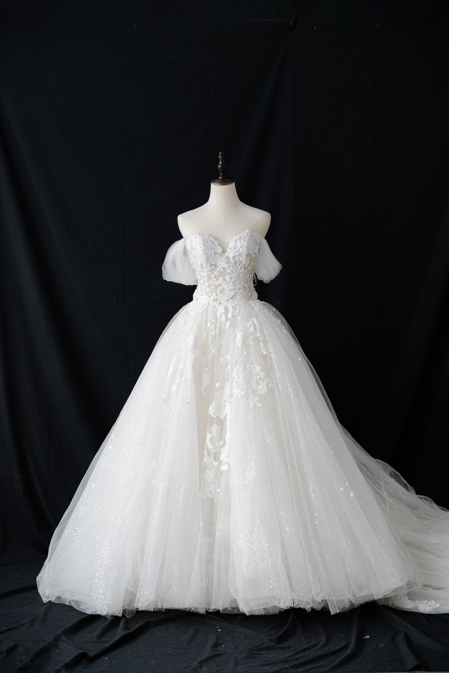 Princess-style wedding dress with beaded bodice and voluminous tulle skirt displayed on mannequin.