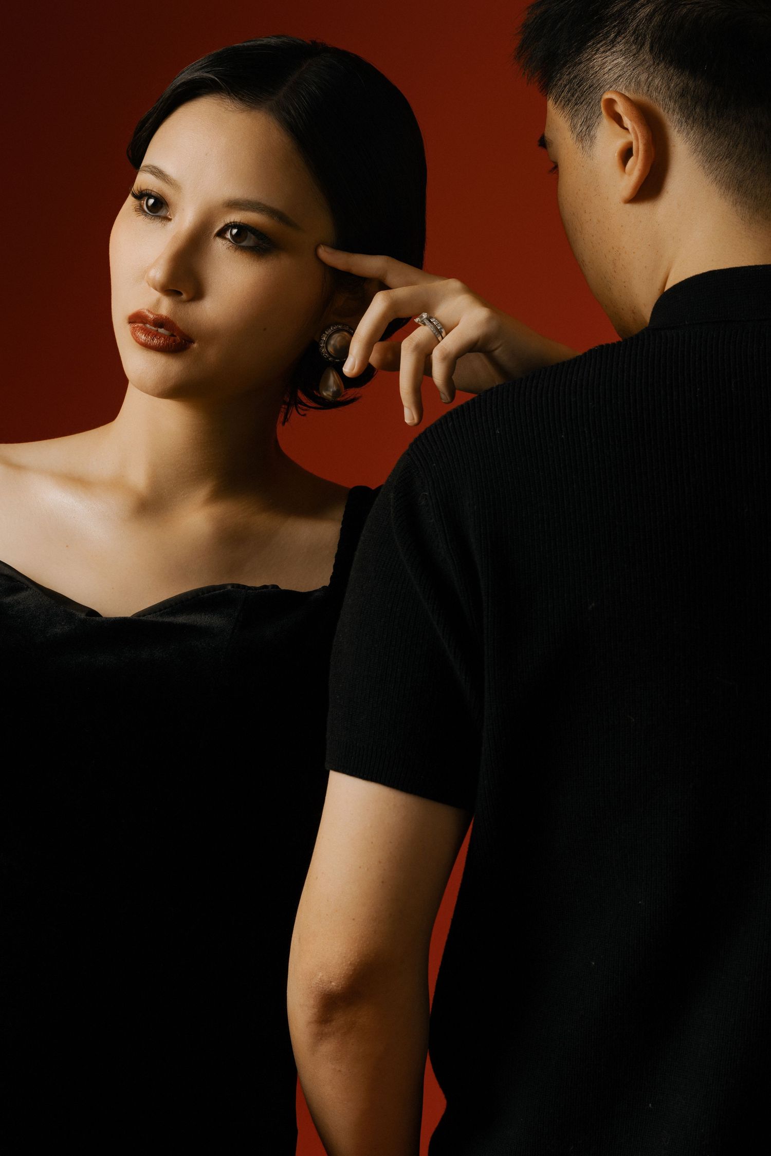 Dramatic black and red portrait series showing intimate couple poses against dark background.