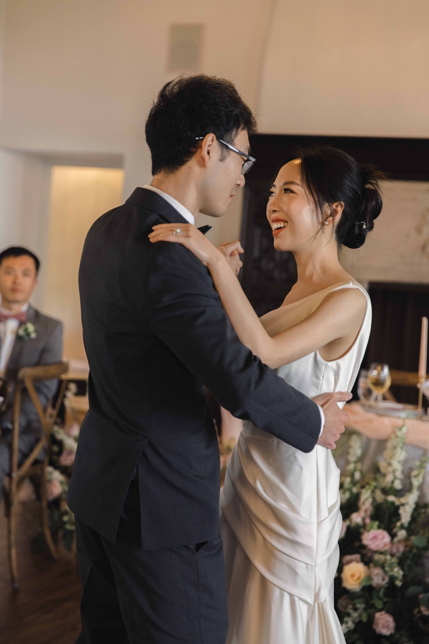 Couple sharing their first dance in an elegant reception hall with chandeliers.