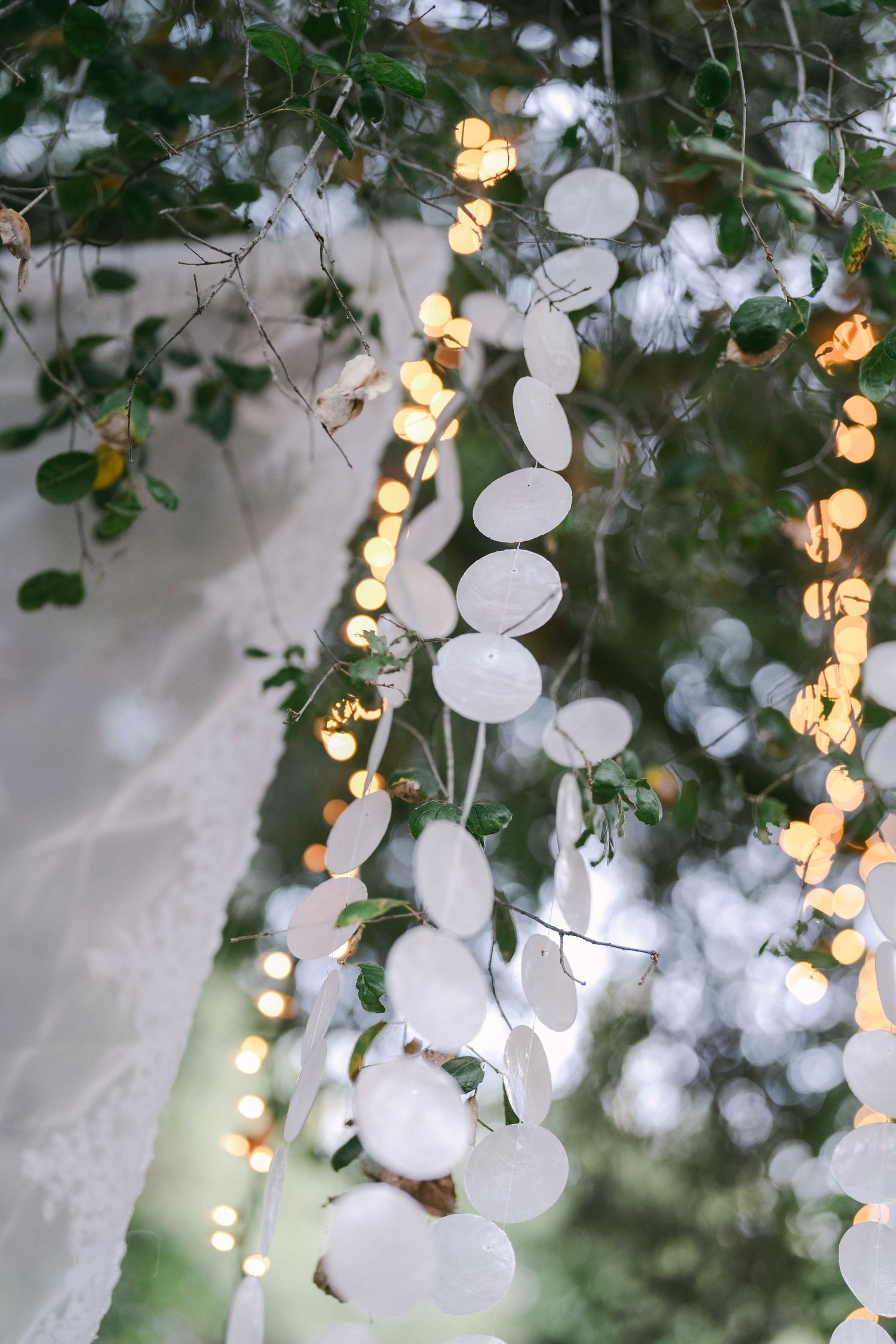 White cotton ball decorations and string lights create a dreamy overhead display at an outdoor event.