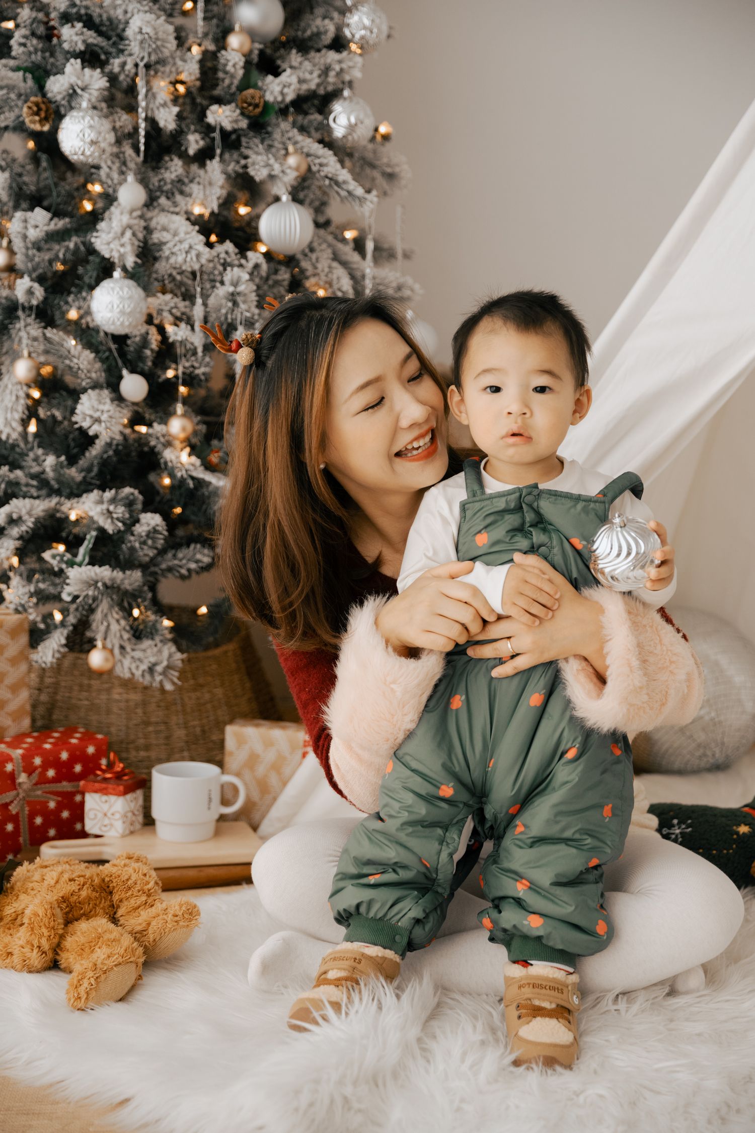 A festive holiday photoshoot with a decorated Christmas tree and cozy white decor.