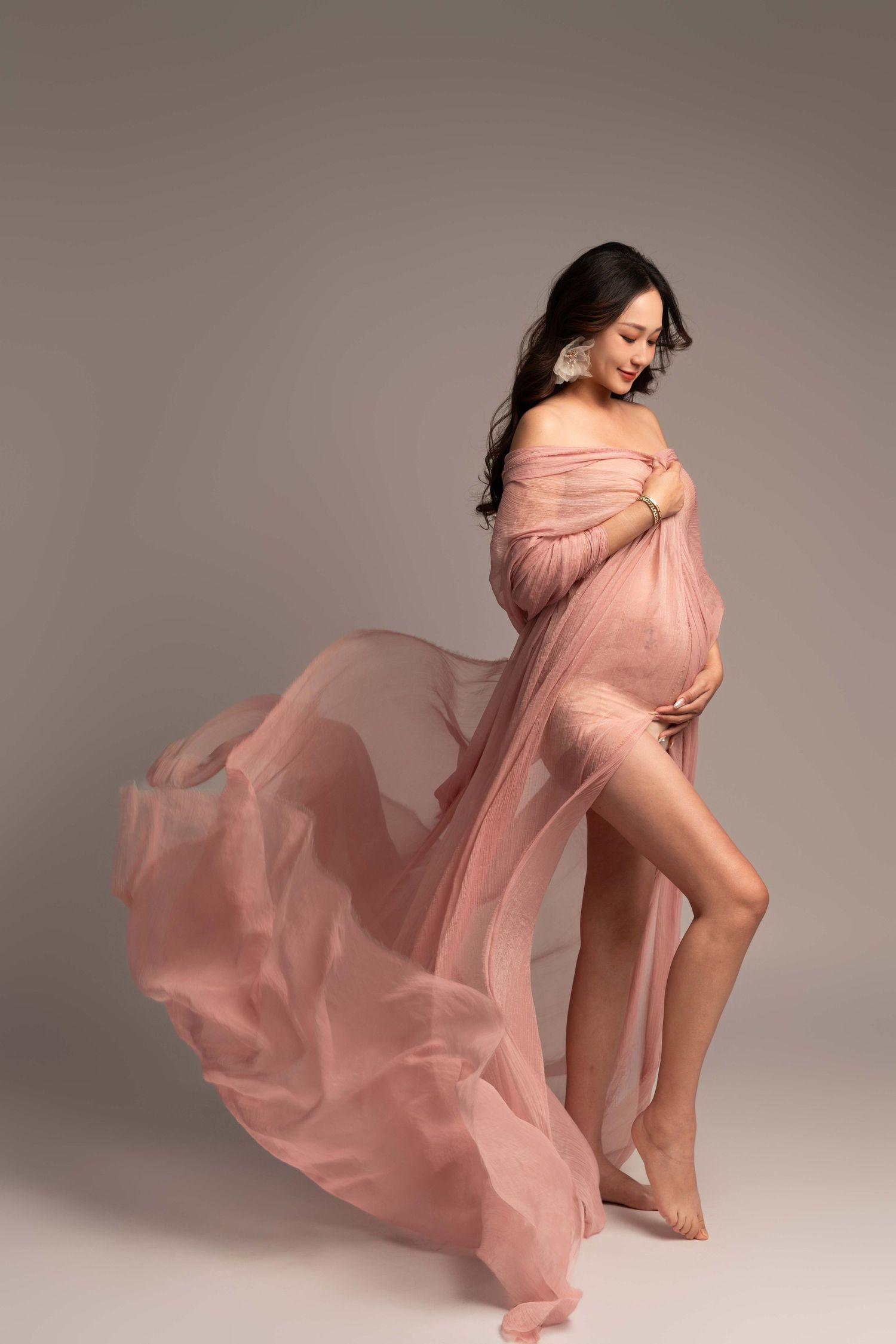 Maternity photo series with billowing pink sheer fabric in studio setting.