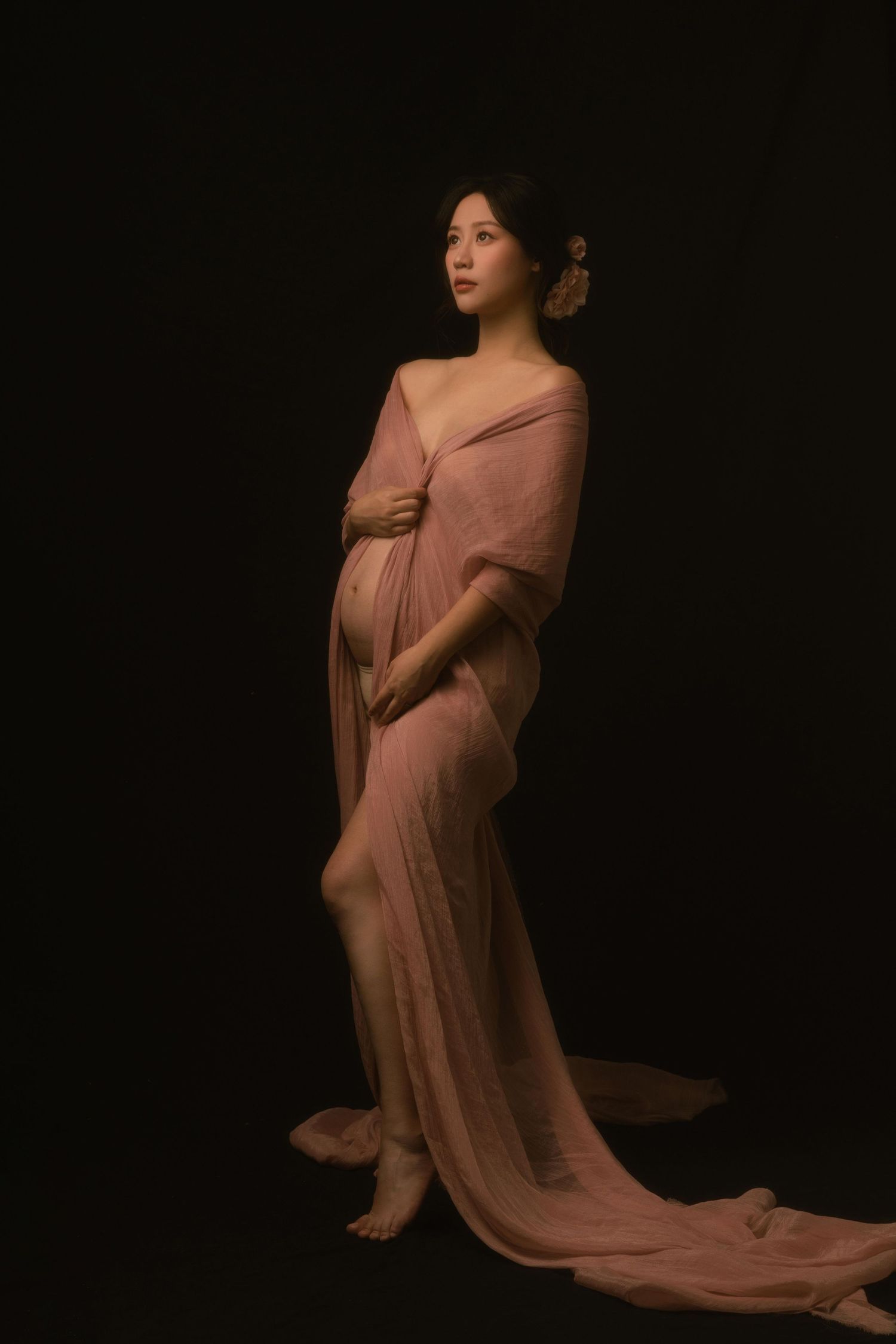Dramatic maternity portraits with flowing dusty rose fabric in low-key lighting.