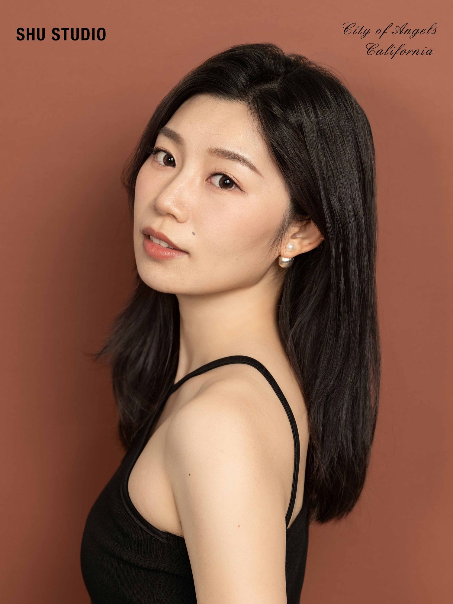 Studio portrait in black tank top against brown background.