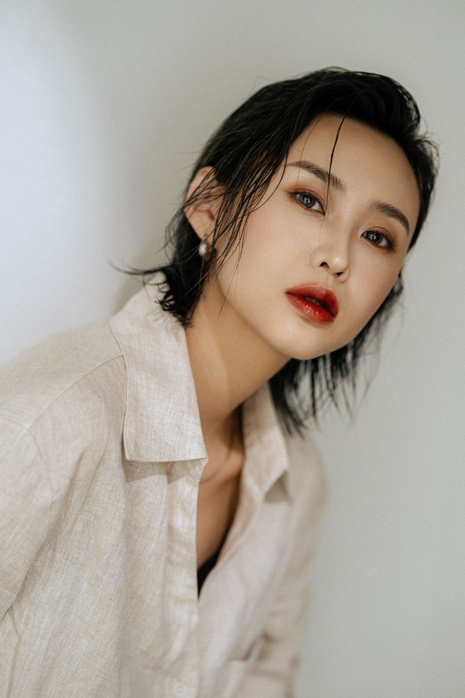 Artistic portrait with dramatic lighting highlighting red lips and textured white shirt.