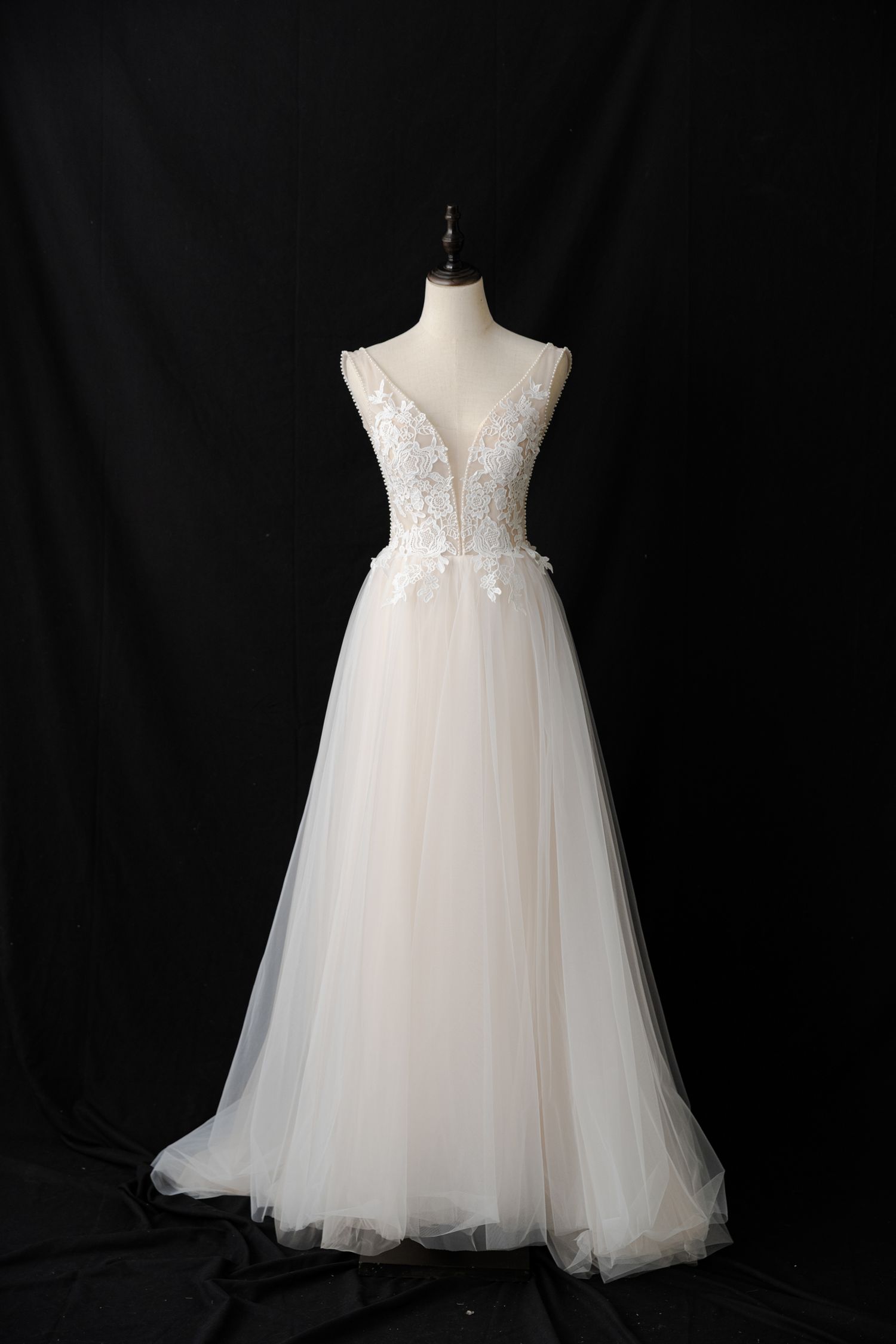 Ethereal white flower girl dress with delicate lace appliques and tulle skirt displayed on mannequin.