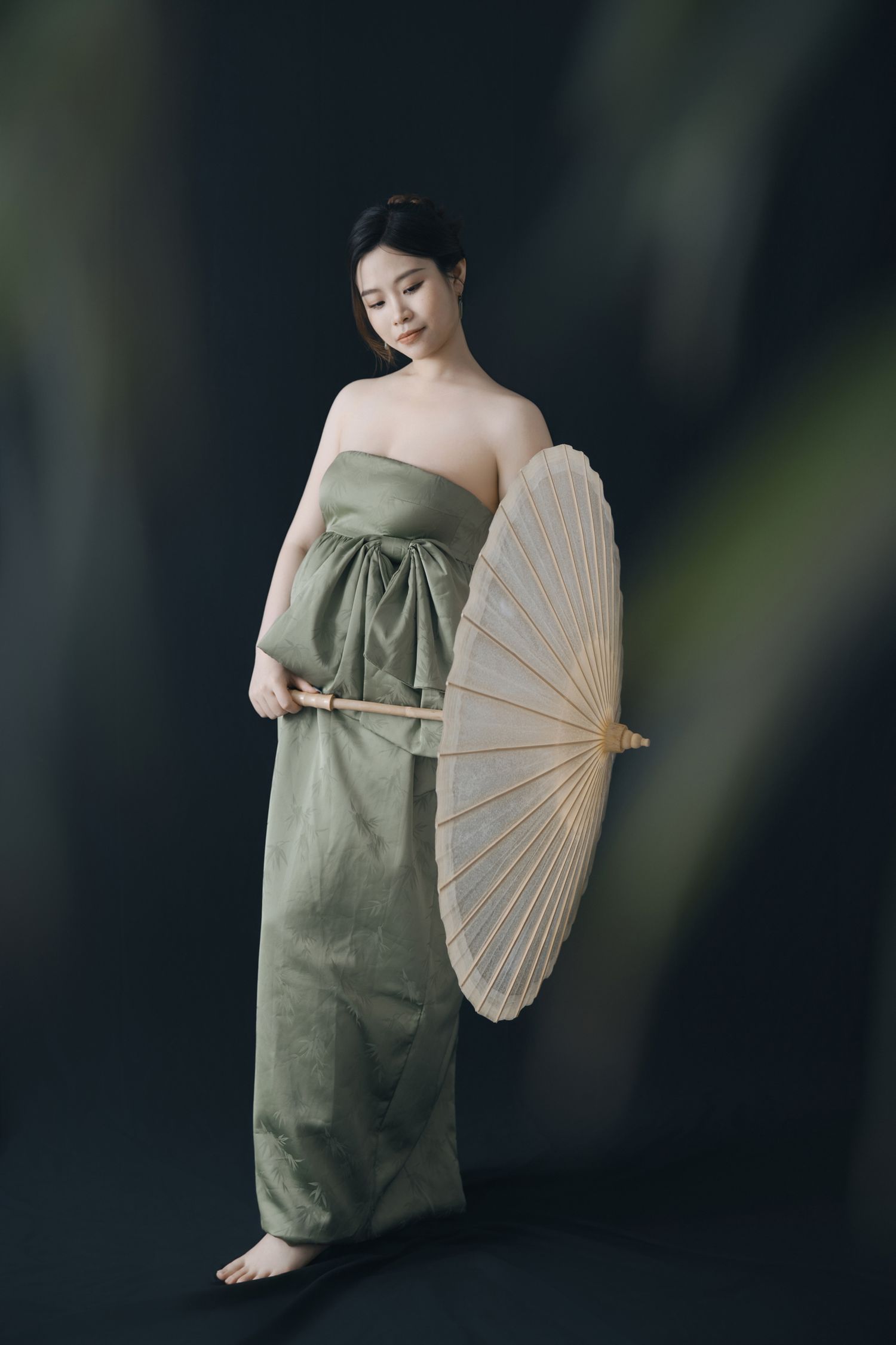 Elegant maternity poses with a traditional paper parasol and olive green flowing dress.