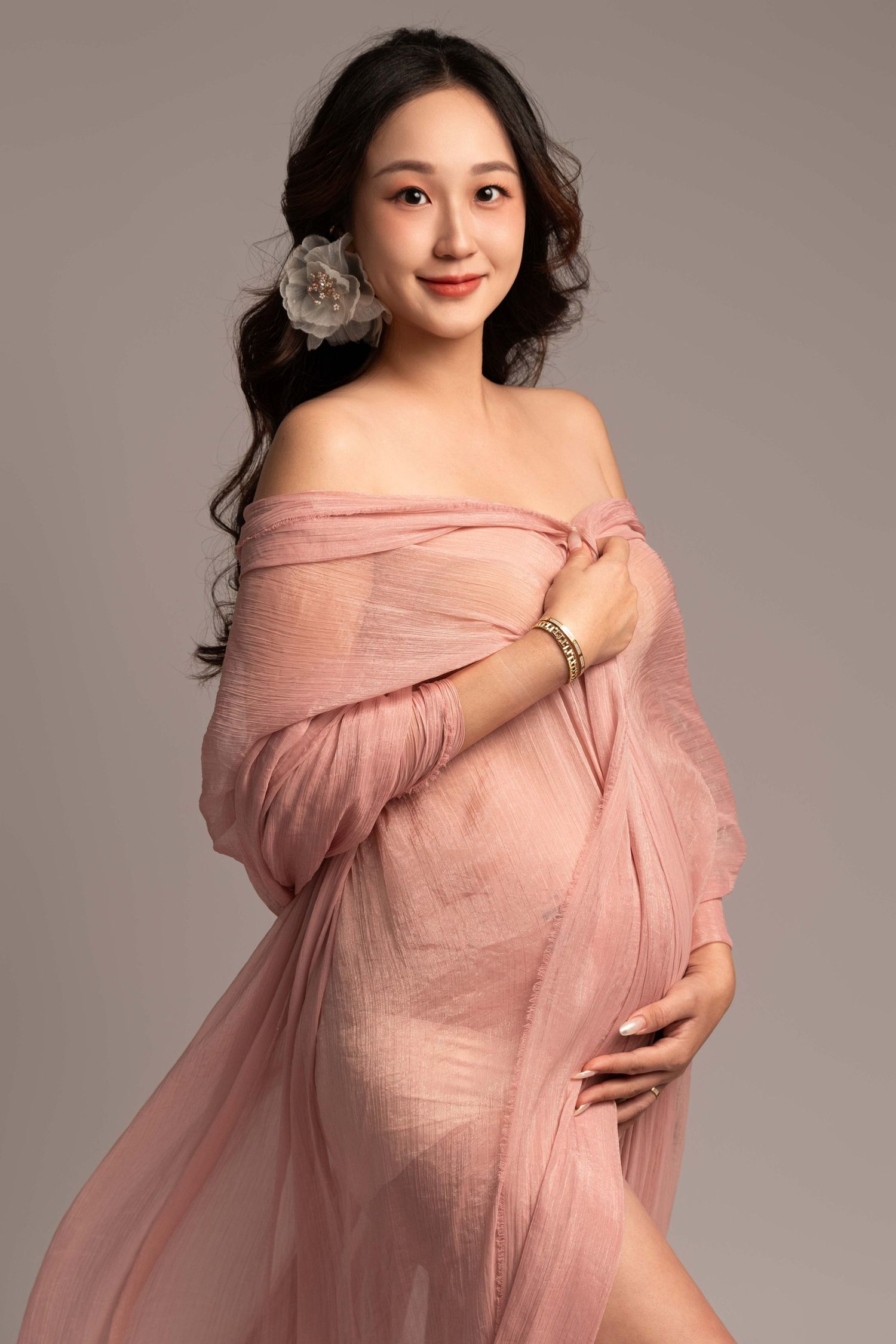 Romantic maternity portraits featuring soft pink off-shoulder wrap dress.