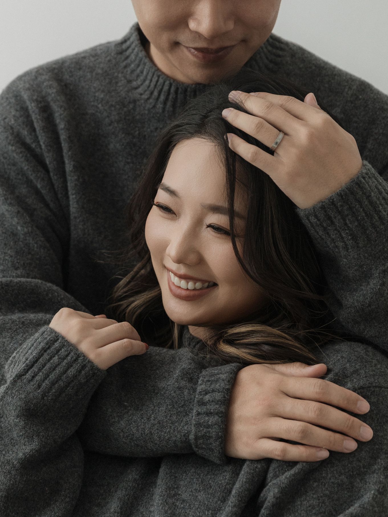 Couple sharing tender moment while wearing matching gray sweaters.
