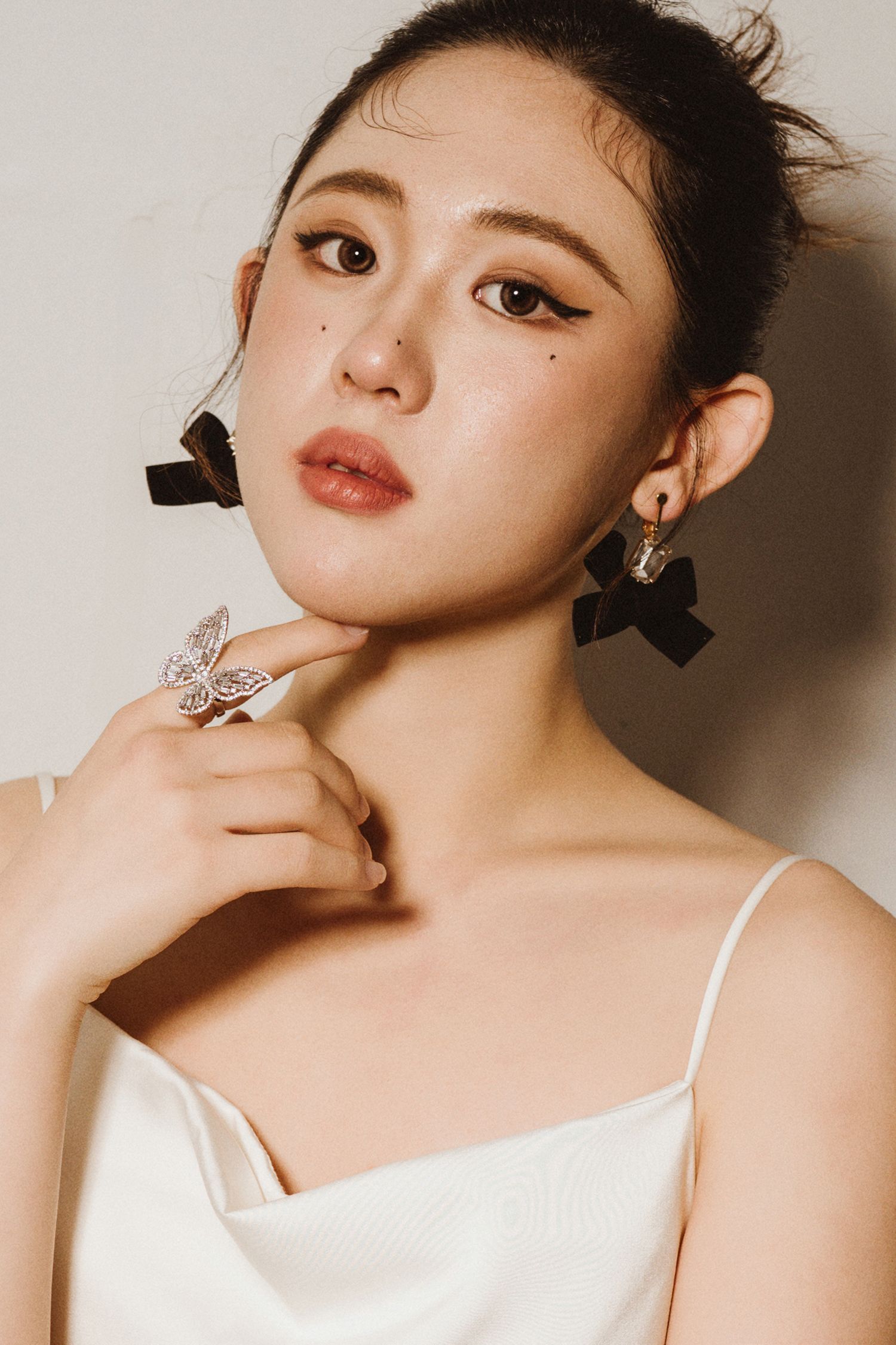 Studio beauty shots featuring butterfly jewelry and classic makeup look.